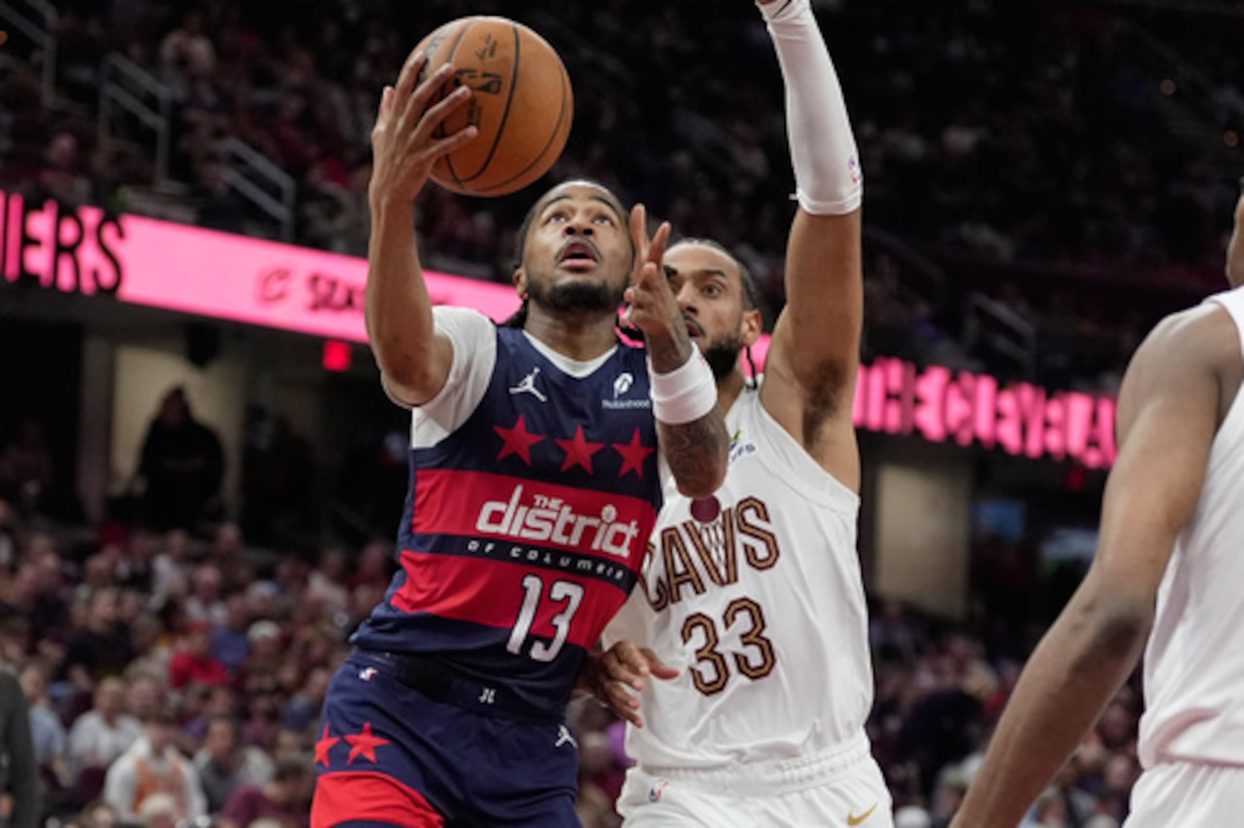 El escolta de los Washington Wizards Sharife Cooper (13) va hacia la canasta superando al alero de los Cleveland Cavaliers Olivier Sarr (33) en la segunda mitad de un partido de baloncesto de la NBA en Cleveland, el domingo 12 de abril de 2026. (AP Photo/Sue Ogrocki)