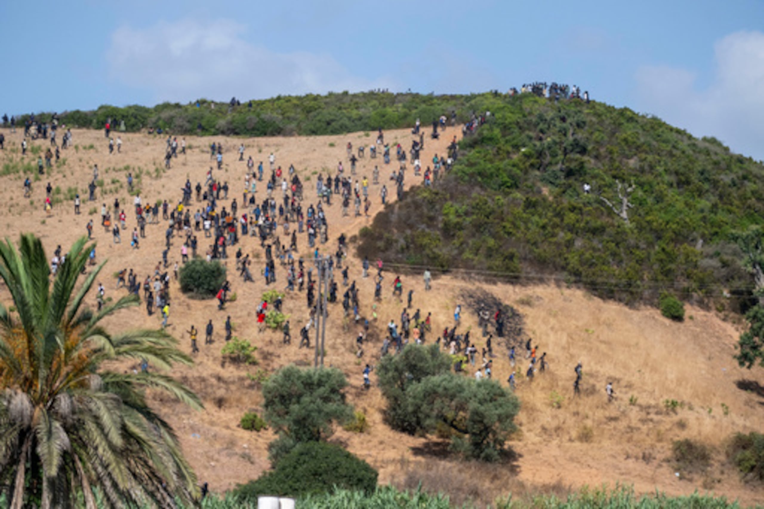 Un grupo de migrantes se reúne en una colina mientras intentan cruzar desde la localidad fronteriza de Fnideq hacia el enclave español de Ceuta, el sábado 15 de agosto de 2026. (Foto: AP)