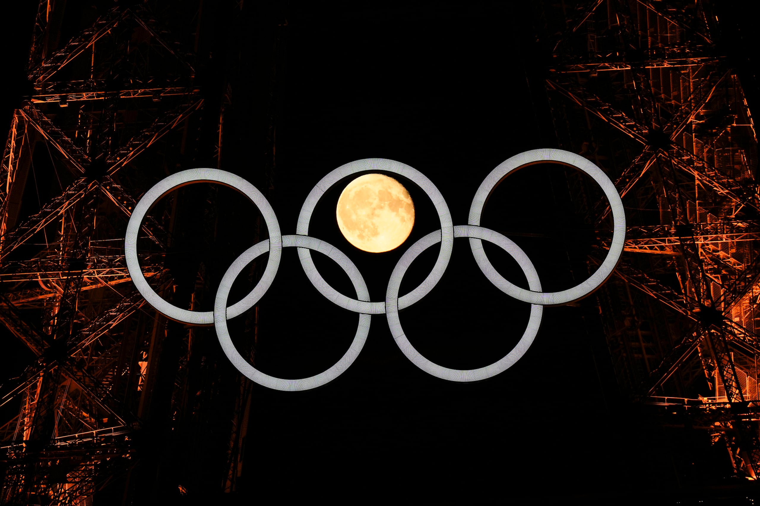 La Luna llena se aprecia detrás de los aros olímpicos en la Torre Eiffel el lunes 22 de julio de 2024.