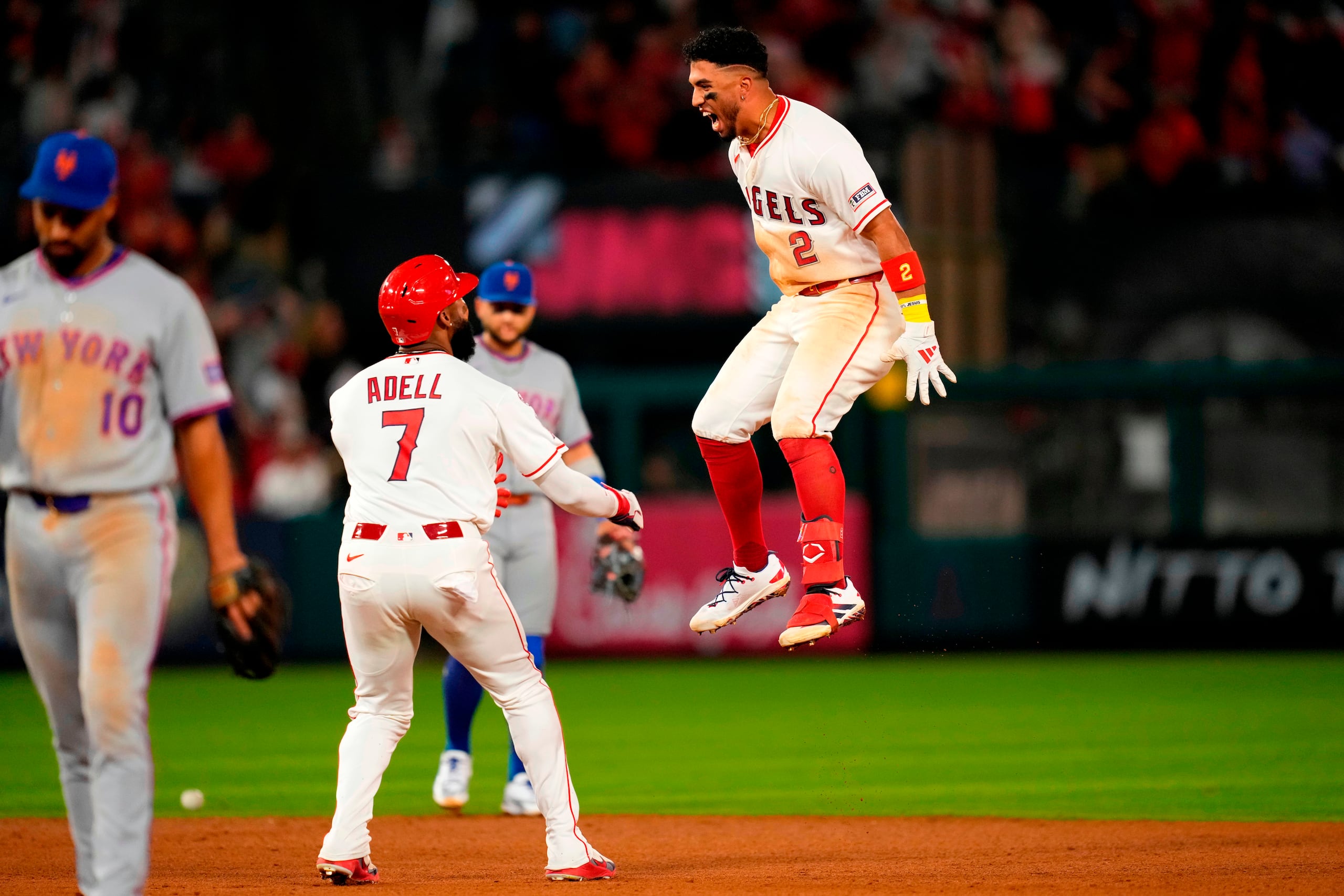 Oswald Peraza, de los Angels de Los Ángeles (derecha), celebra su sencillo de la victoria con Jo Adell (centro), mientras el segunda base de los Mets de Nueva York, Marcus Semien, sale del campo en la décima entrada de un partido de béisbol el sábado 2 de mayo de 2026, en Anaheim, California. (Foto AP/Mark J. Terrill)