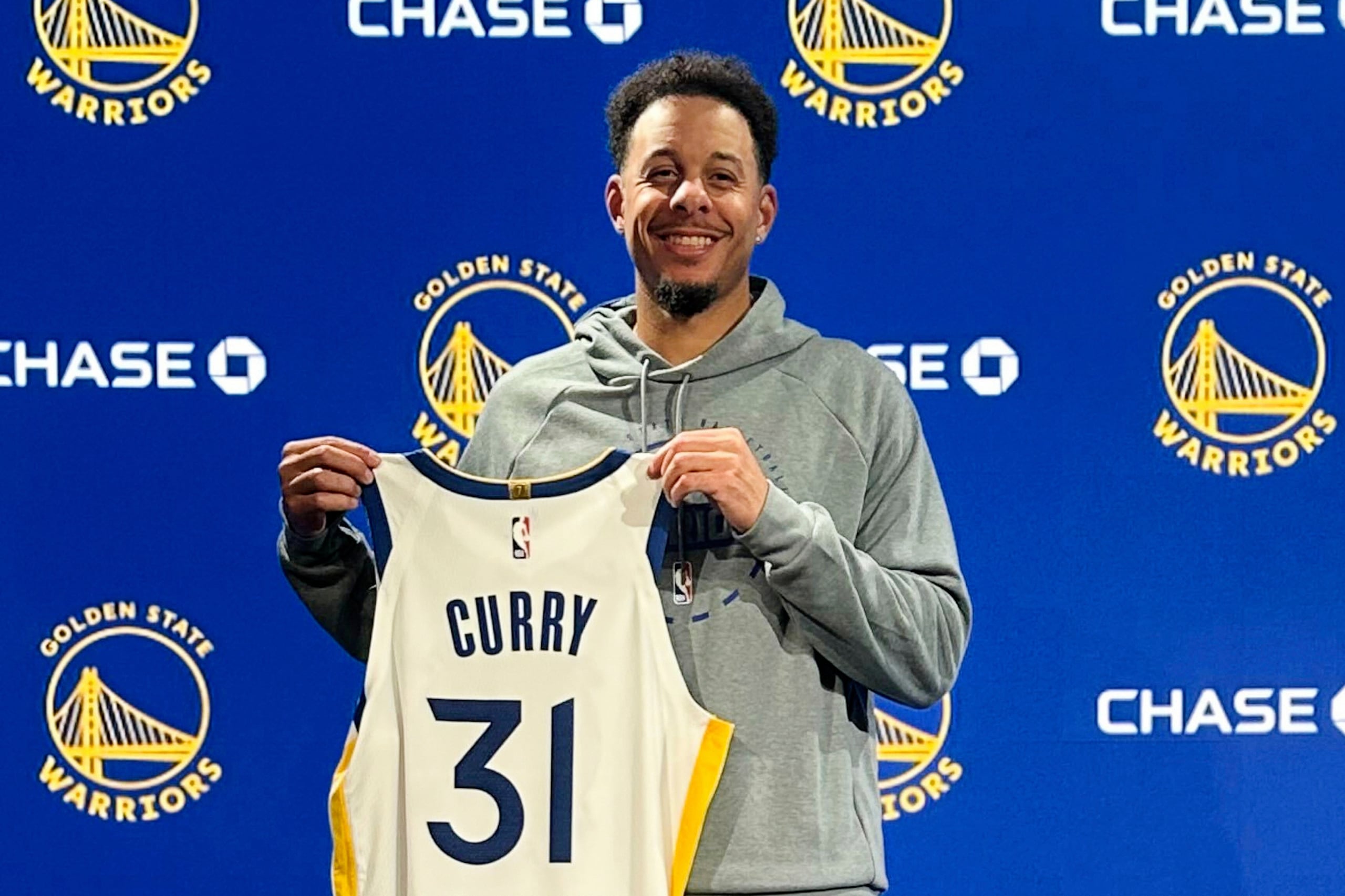 Seth Curry, de los Warriors de Golden State, posa con su camiseta durante una rueda de prensa de presentación de baloncesto de la NBA, el jueves 2 de octubre de 2025, en San Francisco.