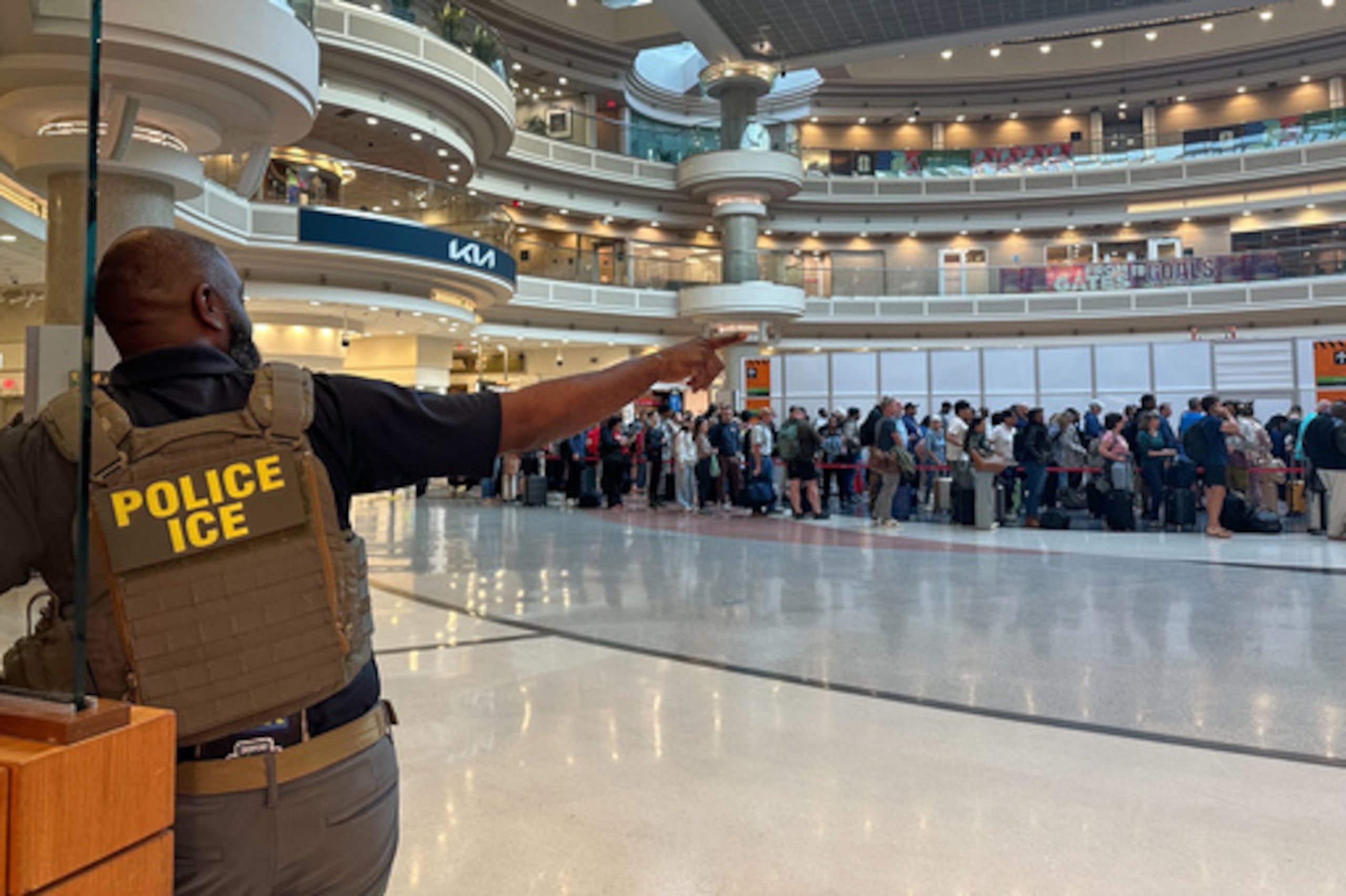 Un agente federal de inmigración es visto mientras la gente espera en una línea de TSA en el Aeropuerto Internacional Hartsfield-Jackson de Atlanta, el lunes 23 de marzo de 2026, en Atlanta. (AP Photo/Emilie Megnien)
