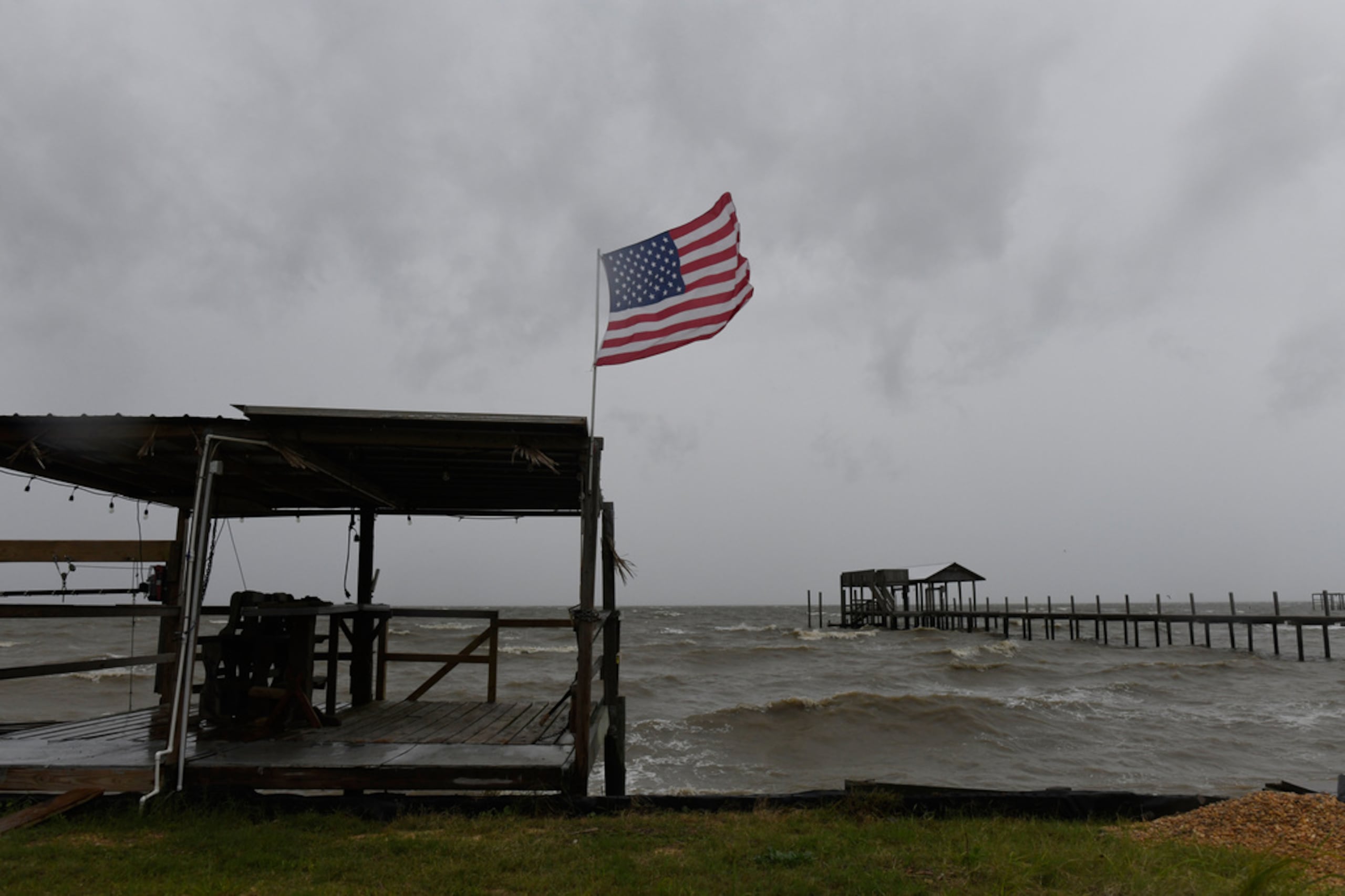 Una bandera estadounidense ondea al viento provocado por los efectos del huracán Isaías en una playa vacía, el 9 de octubre de 2026, en Mon Louis Island, Alabama.