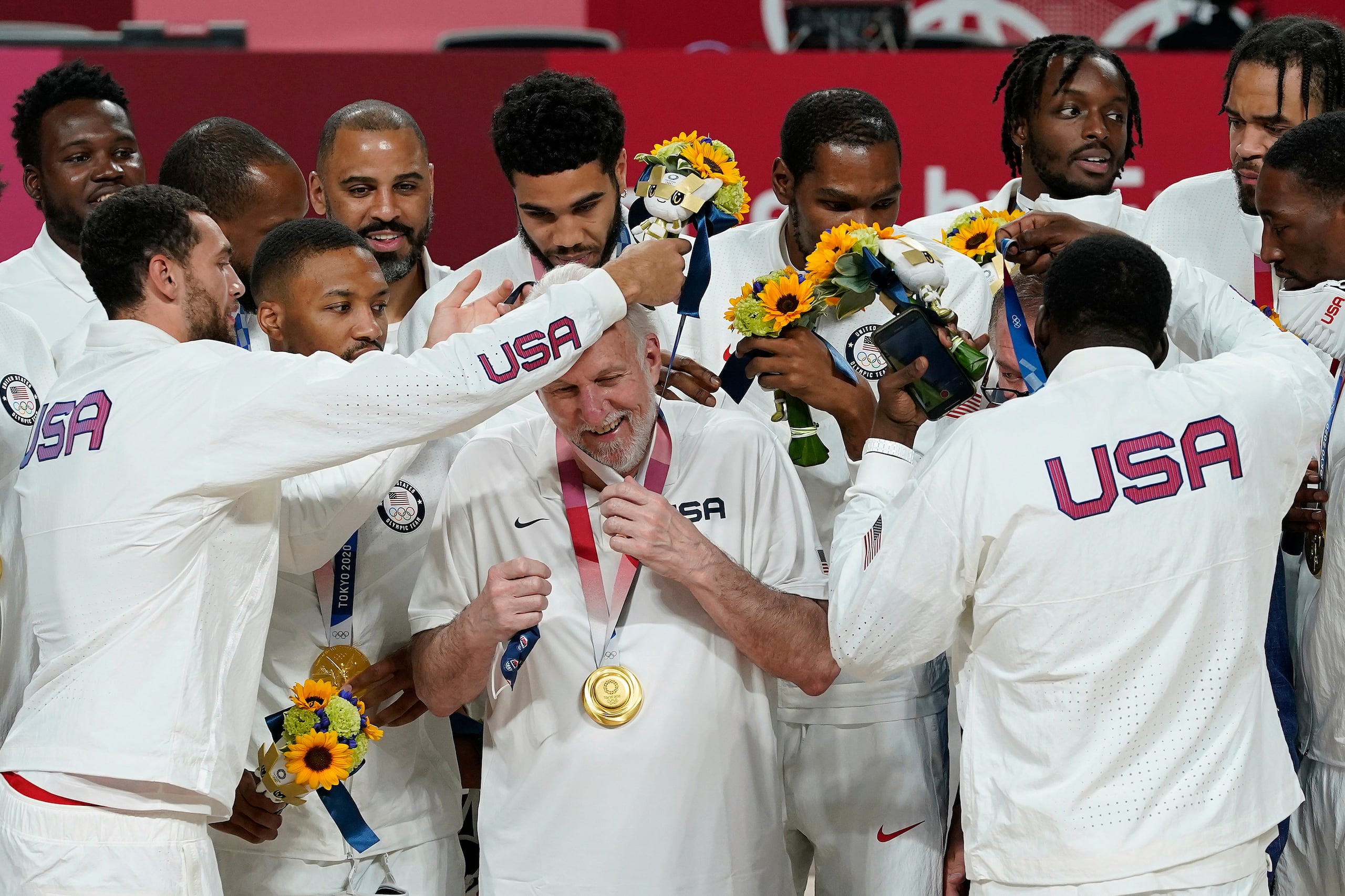 En esta foto del sábado 7 de agosto del 2021, jugadores de la selección de Estados Unidos le colocan la medalla de oro al entrenador Greg Popovich durante la ceremonia de preseas en los Juegos Olímpicos de Tokio.