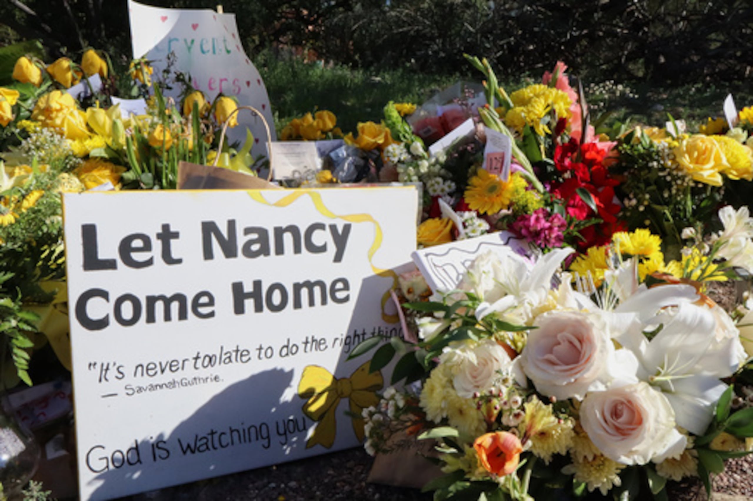 Un monumento crece fuera de la casa de Nancy Guthrie, la madre desaparecida de la presentadora del programa "Today" Savannah Guthrie, el domingo 22 de febrero de 2026, en Tucson, Arizona (AP Photo/Felicia Fonseca)