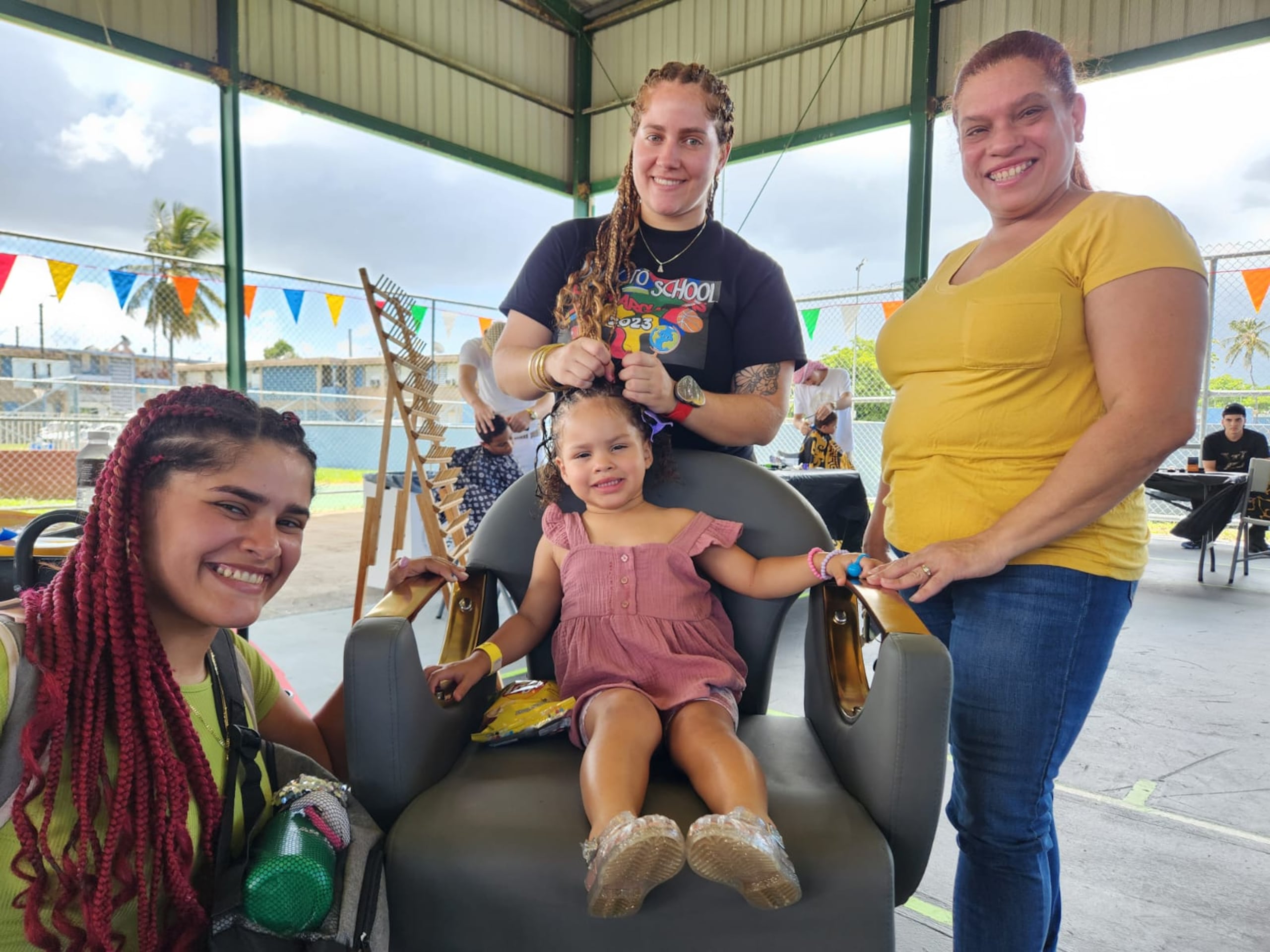 La pequeña Anaila Lisboa Rodríguez recibe sus trenzas por parte de Ilene Otero López. Mientras. Elba Marie Rodríguez Díaz y Elba Díaz Soto disfrutan el momento.