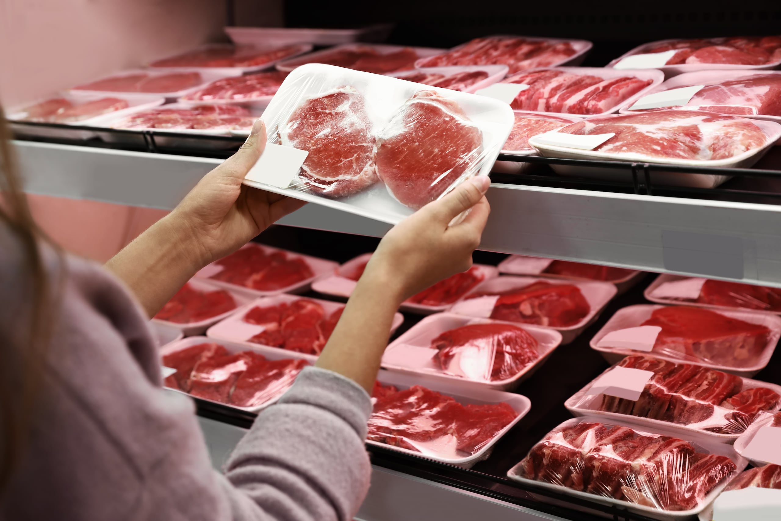 Una mujer compra carne en un supermercado.