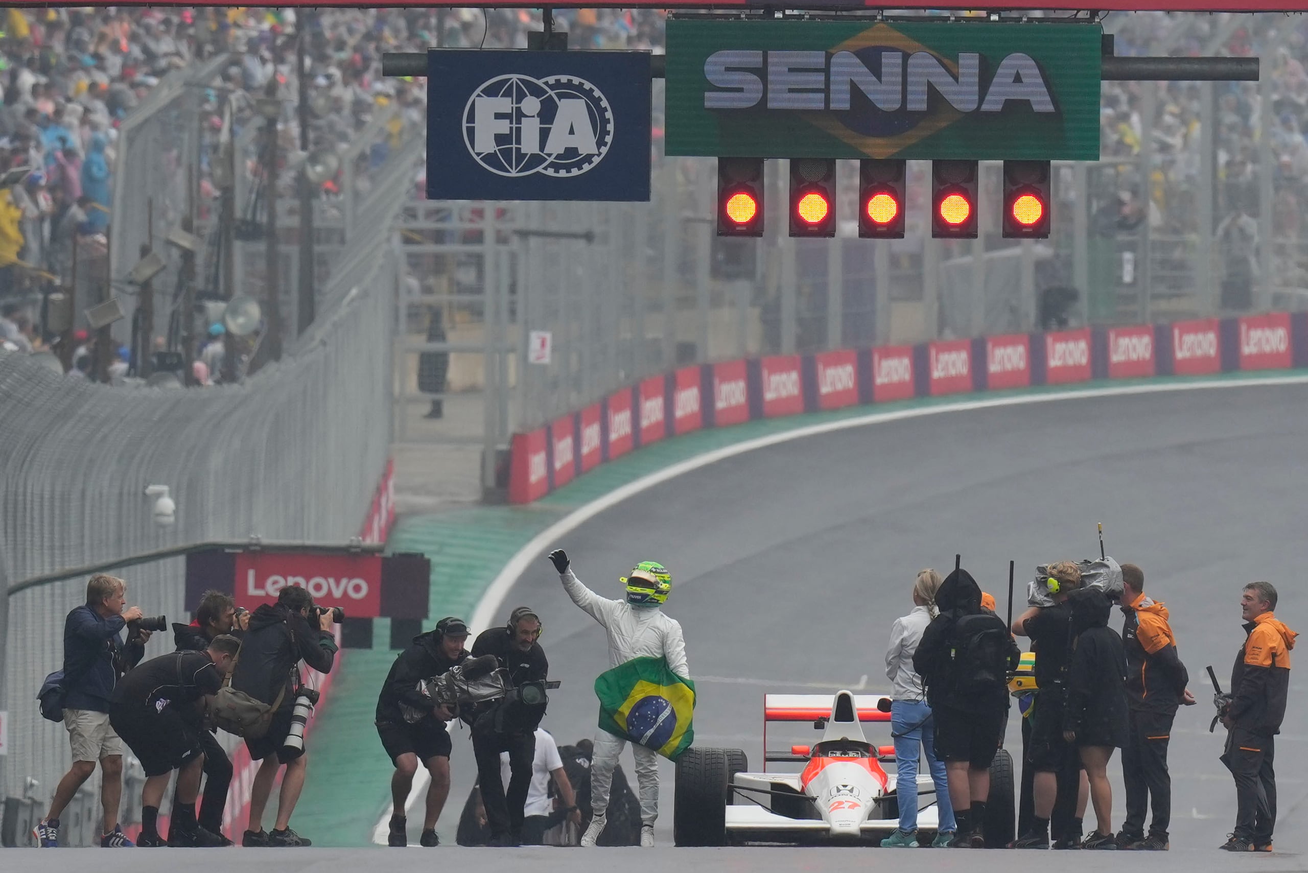 El piloto británico de Mercedes, Lewis Hamilton (centro), saluda a los fanáticos luego de conducir el auto del legendario piloto Ayrton Senna previo al Gran Premio de Brasil en la Formula 1, en el circuito de Interlagos, en Sao Paulo, Brasil, el domingo 3 de noviembre de 2024.
