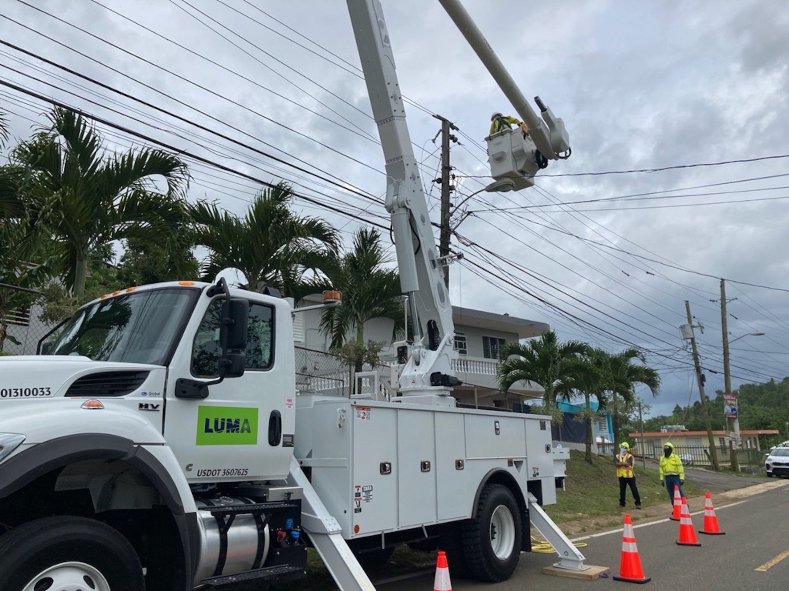 Empleados de LUMA realizan tareas en un poste del tendido eléctrico.