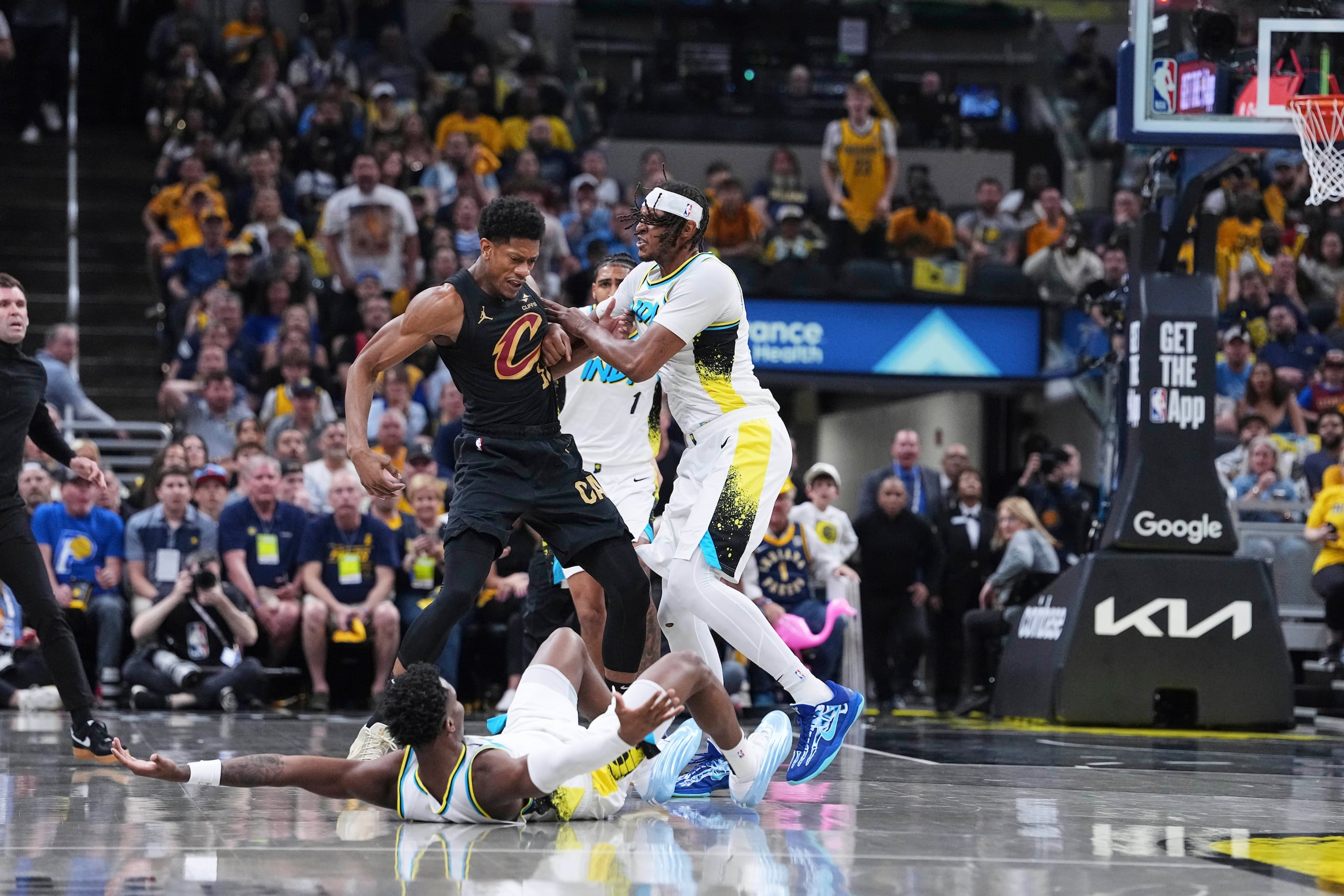 El escolta de los Pacers de Indiana, Bennedict Mathurin (00), cae a la cancha mientras el pívot Myles Turner empuja al alero de los Cavaliers de Cleveland, De'Andre Hunter (12), en la primera mitad del Juego 4 de las semifinales de la Conferencia Este de los playoffs de baloncesto de la NBA en Indianápolis, el domingo 11 de mayo de 2025. (AP Foto/Michael Conroy)