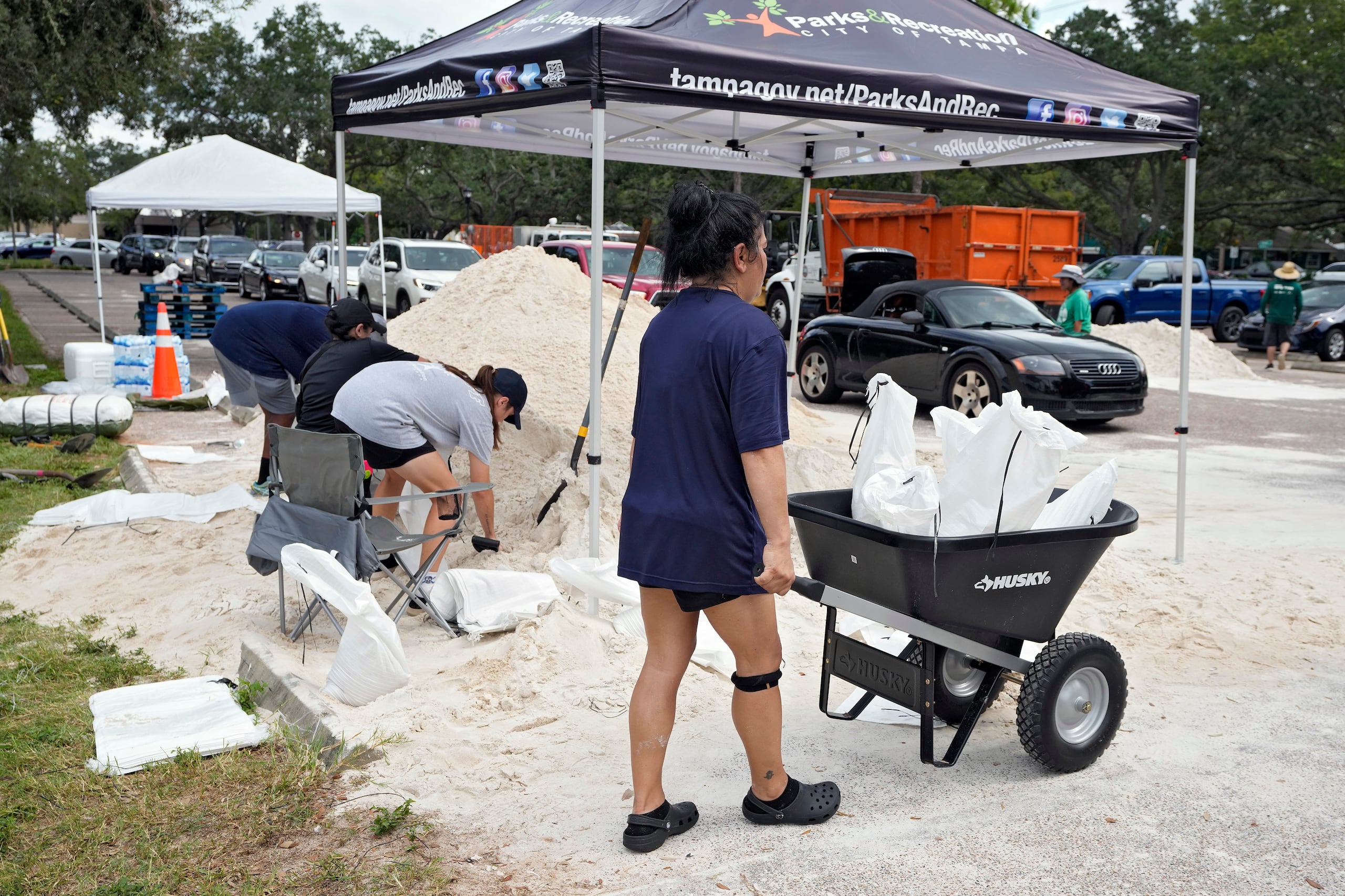 Elementos del Departamento de Parques y Recreación de Tampa, Florida, entregan costales de arena a los residentes, el lunes 28 de agosto de 2023, en Tampa. (AP Foto/Chris O'Meara)