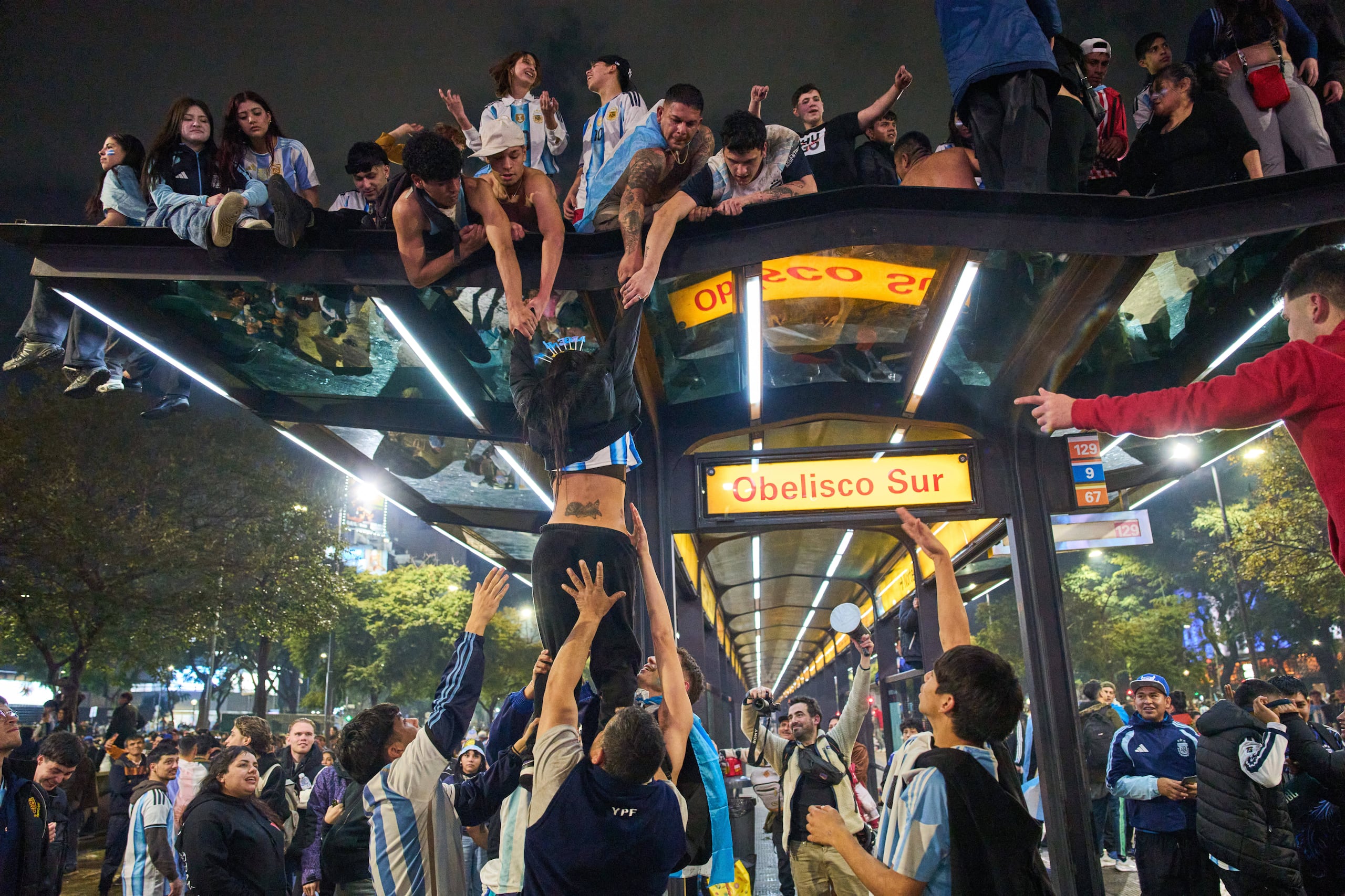 Un grupo de hinchas de Argentina se trepan encima del techo de una estación de autobuses durante los festejos de la victoria ante Inglaterra en las semifinales del Mundial, el miércoles 15 de julio de 2026, en Buenos Aires. (AP Foto/Rodrigo Abd)