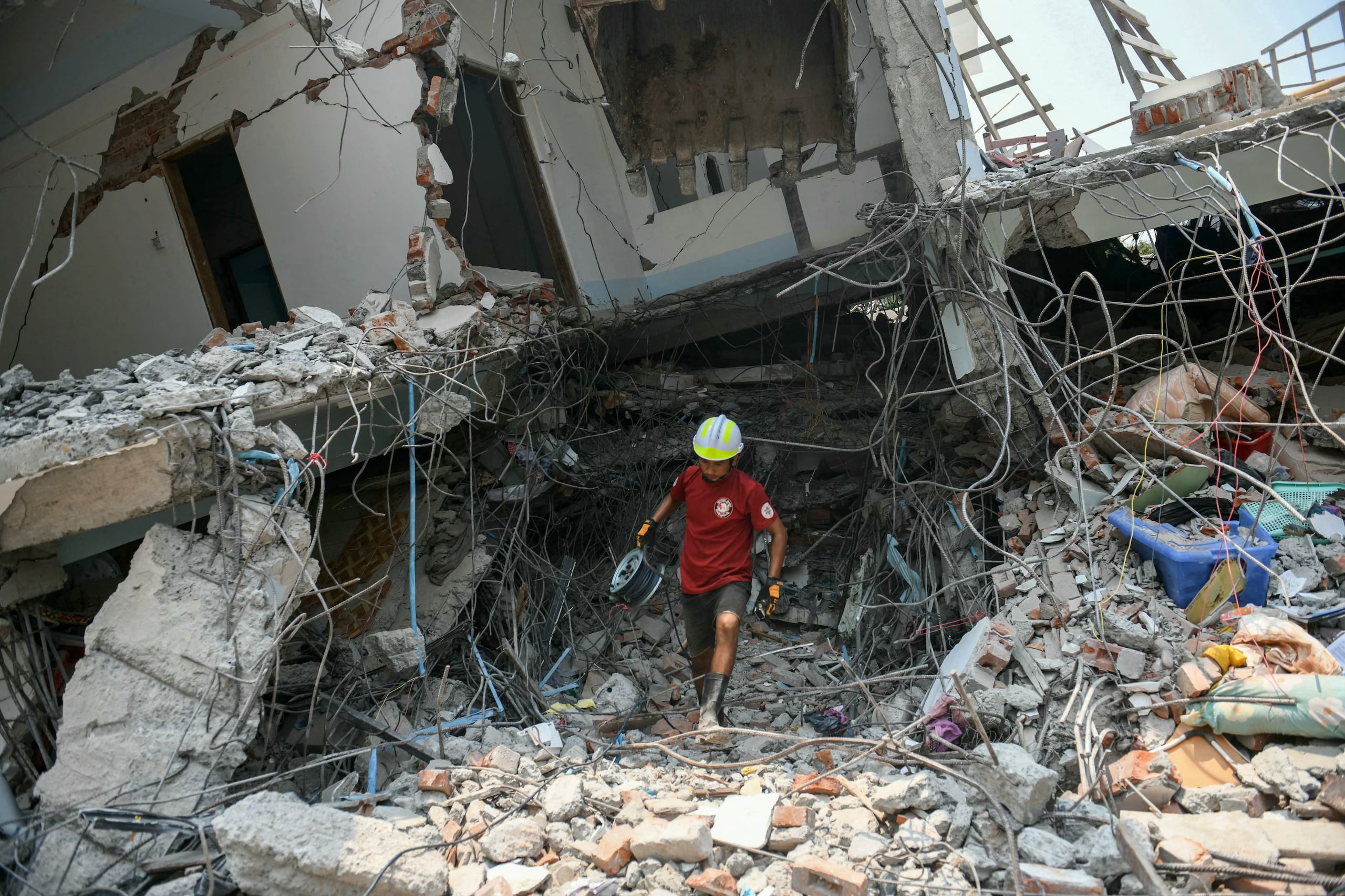 Un rescatista camina entre los escombros en medio de los esfuerzos por conseguir sobrevivientes en Birmania.