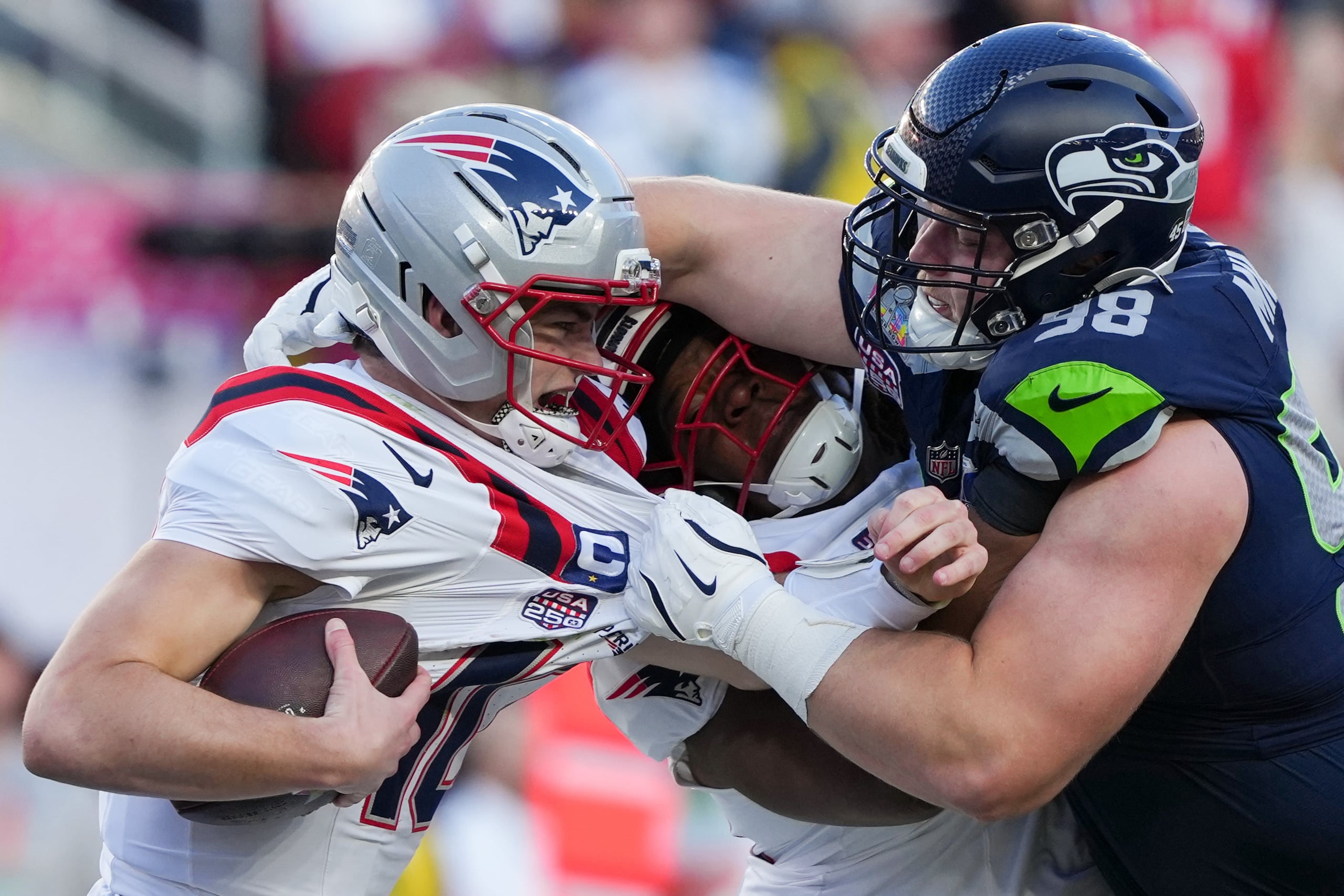 El jugador defensivo de los Seahawks, Rylie Mills, derriba al quarterback de los Patriots, Drake Maye.