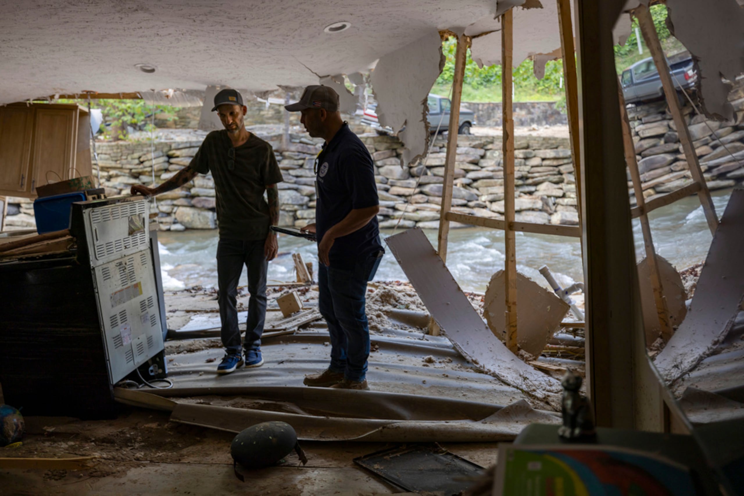 El empleado de FEMA, Jirau Alvaro, trabaja con Daniel Mancini en la realización de un informe sobre los daños a su propiedad el 6 de octubre de 2024 en la zona rural del condado de Buncombe, cerca de Black Mountain, Carolina del Norte.