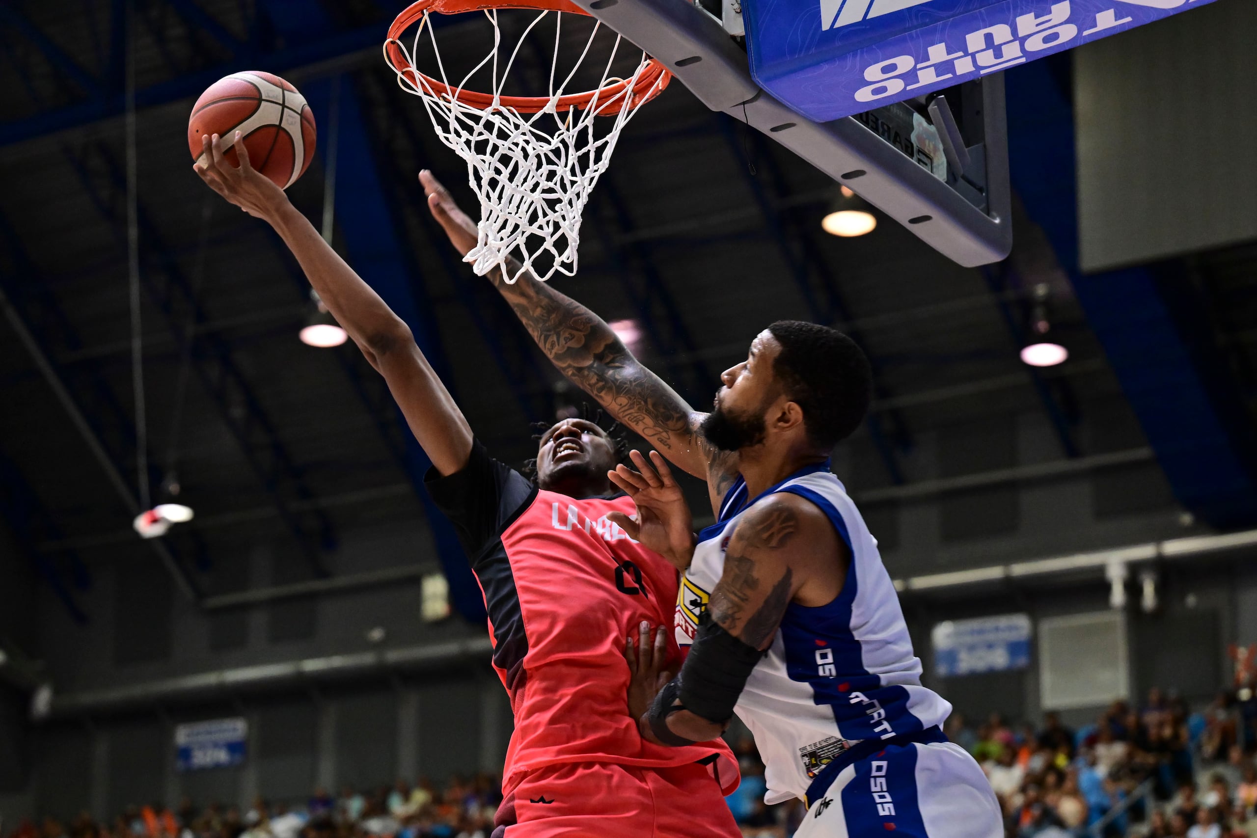 Louis King, de los Criollos de Caguas, ataca el canasto frente a Chris Ortiz, de los Osos de Manatí, durante la serie final del Baloncesto Superior Nacional (BSN) 2024.