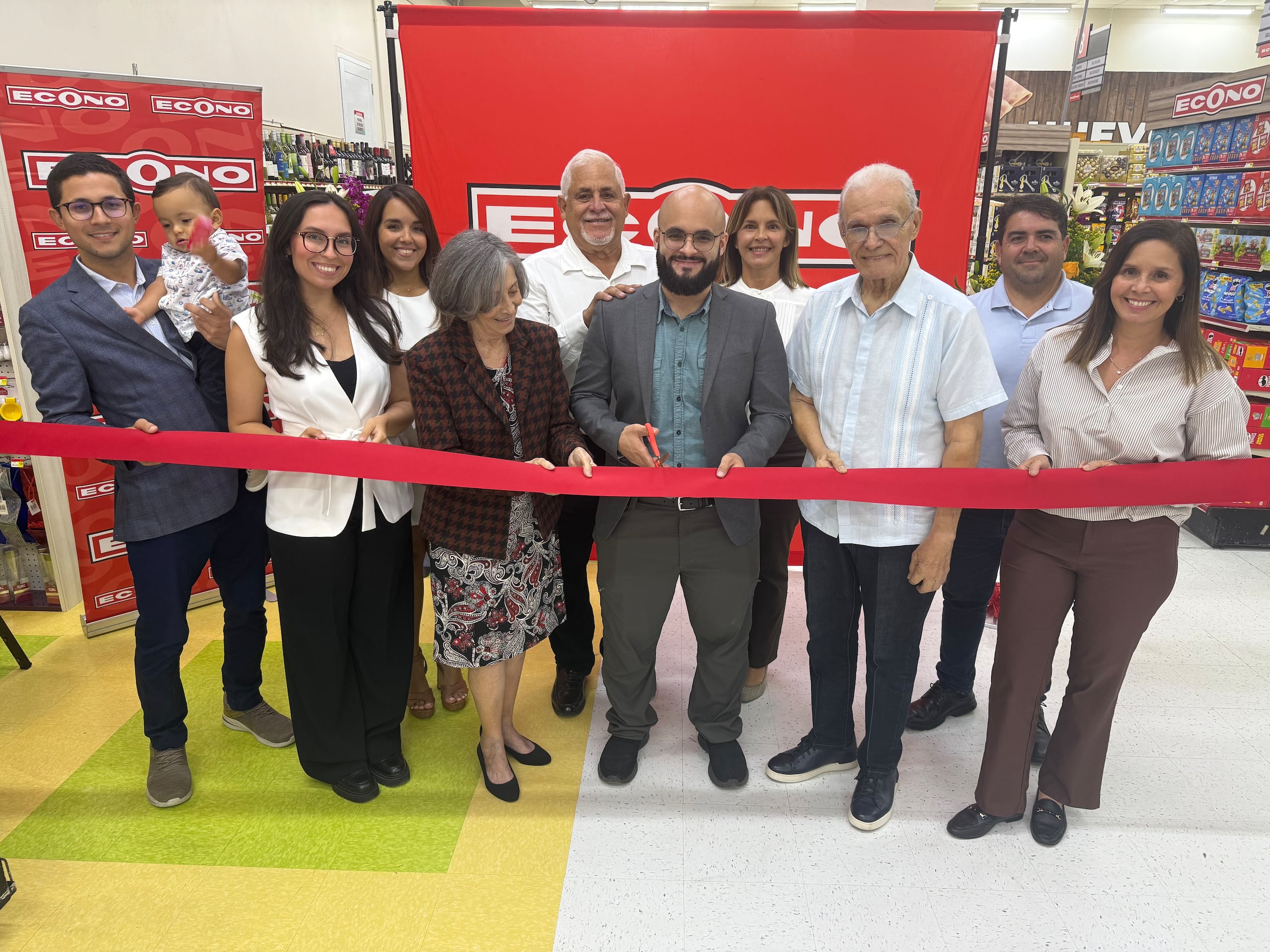 Momento del corte de cinta que marca la apertura de la nueva tienda de Supermercados Econo en Aguada. Al centro, Andrés Javier Ruíz Pérez, gerente de Econo en Aguada, flanqueado por doña Brunilda Medina y don Luis Pérez, socio de Econo. De izquierda a derecha, Luis Alejandro Pérez Carrero con su niño Alejandro Matteo, Arianna del Valle, Noheli Torres, Andrés Ruíz y Cynthia Pérez Medina, y René DiCristina y Verónica Pérez Medina.