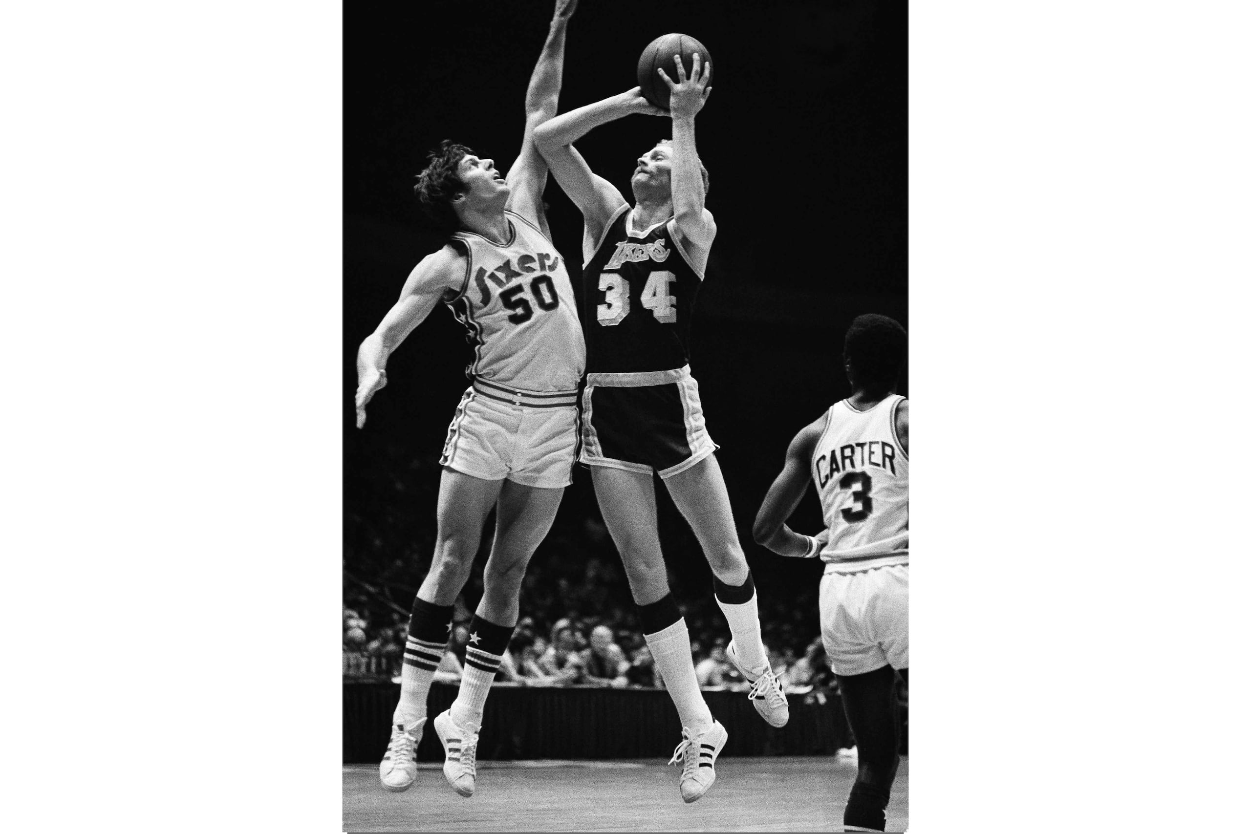 En esta foto del 9 de enero de 1975, Stan Love, de los Lakers de Los Ángeles, intenta anotar mientras lo defiende Steve Mix de los 76ers de Filadelfia.