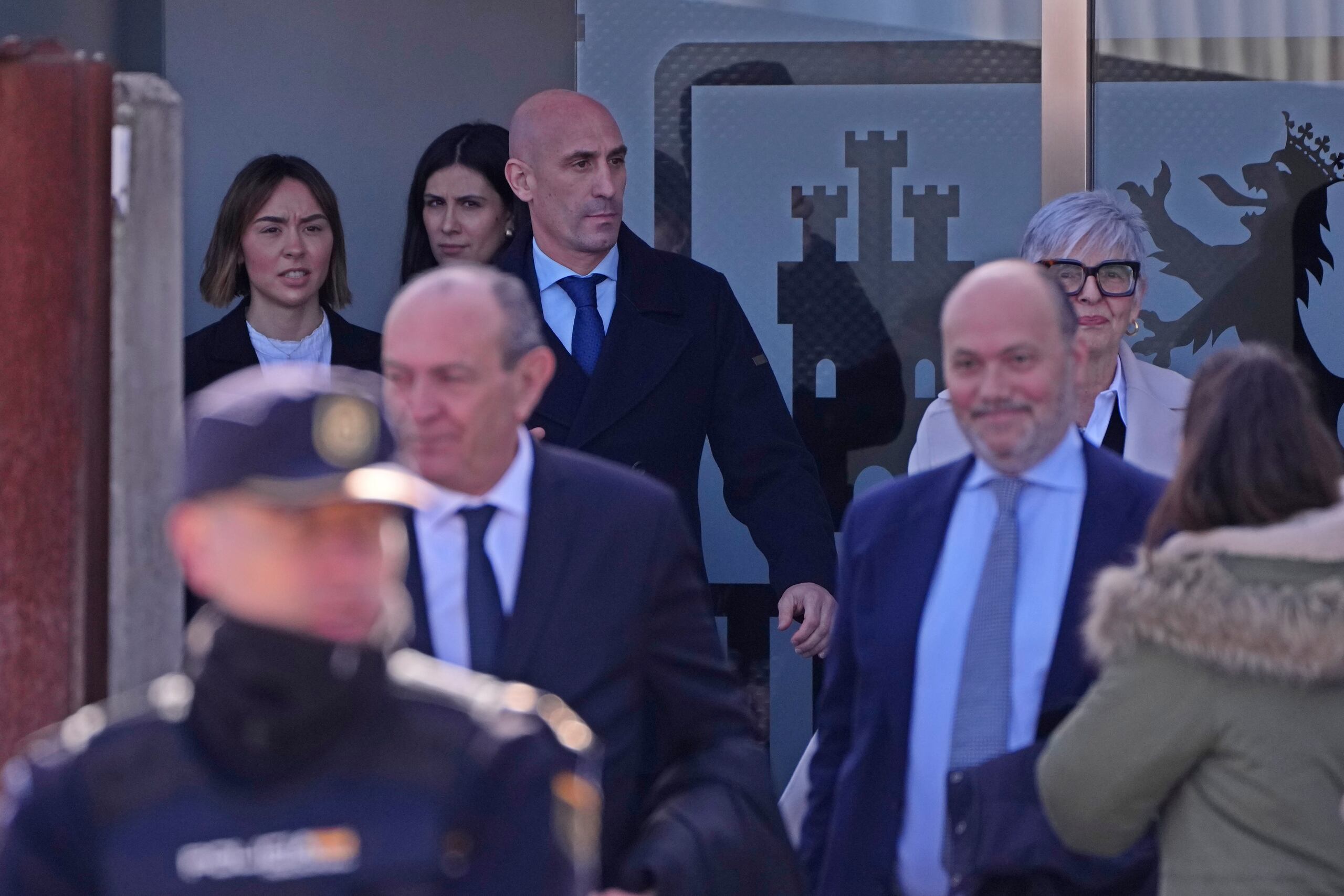 El expresidente de la federación española de fútbol Luis Rubiales (al fondo) se retira del tribunal donde se le enjuicia por besar sin su consentimiento a Jenni Hermoso. (AP Foto/Manu Fernández)