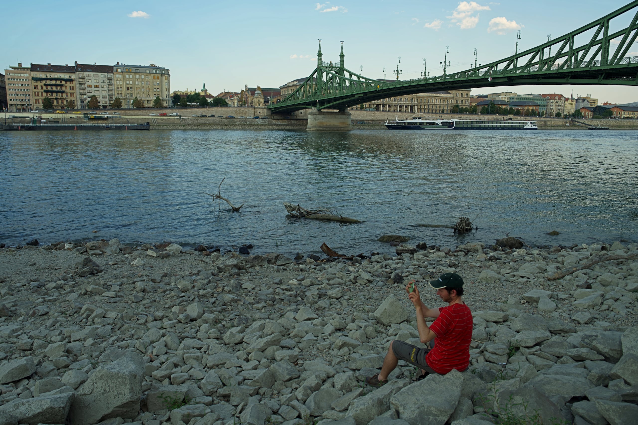 Un hombre toma fotografías desde la orilla seca del río Danubio, en el centro de Budapest, Hungría. (AP Foto/Bela Szandelszky)