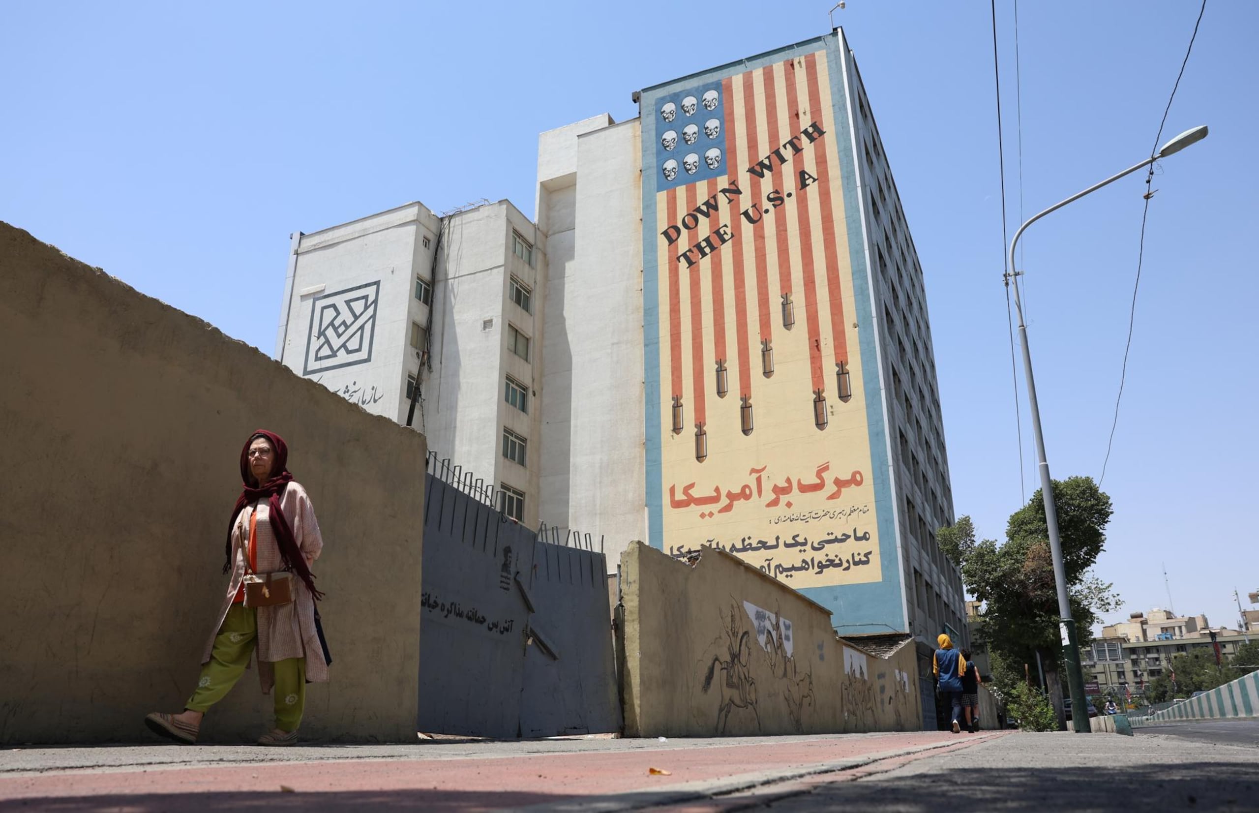 Una mujer iraní camina junto a un mural antiestadounidense en una calle de Teherán, Irán, el 9 de julio de 2026.