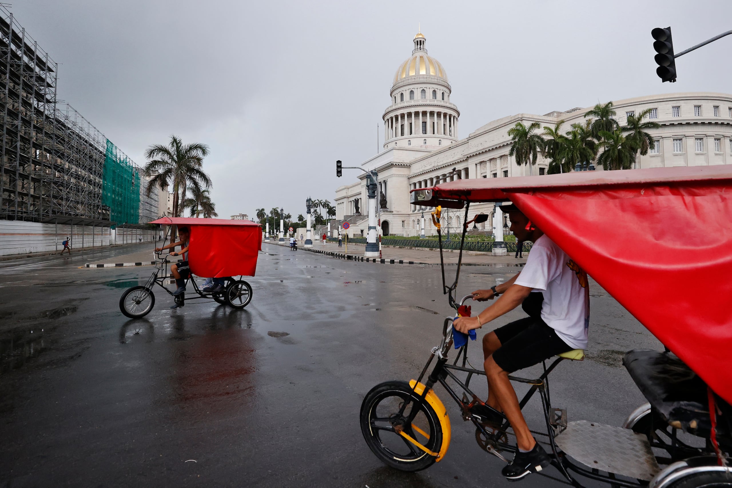 Un par de bicitaxis fue captado este 11 de julio frente al Capitolio de La Habana (Cuba), mientras el país padece el segundo apagón eléctrico nacional de esta semana y el cuarto del año. E(FE/Ernesto Mastrascusa)