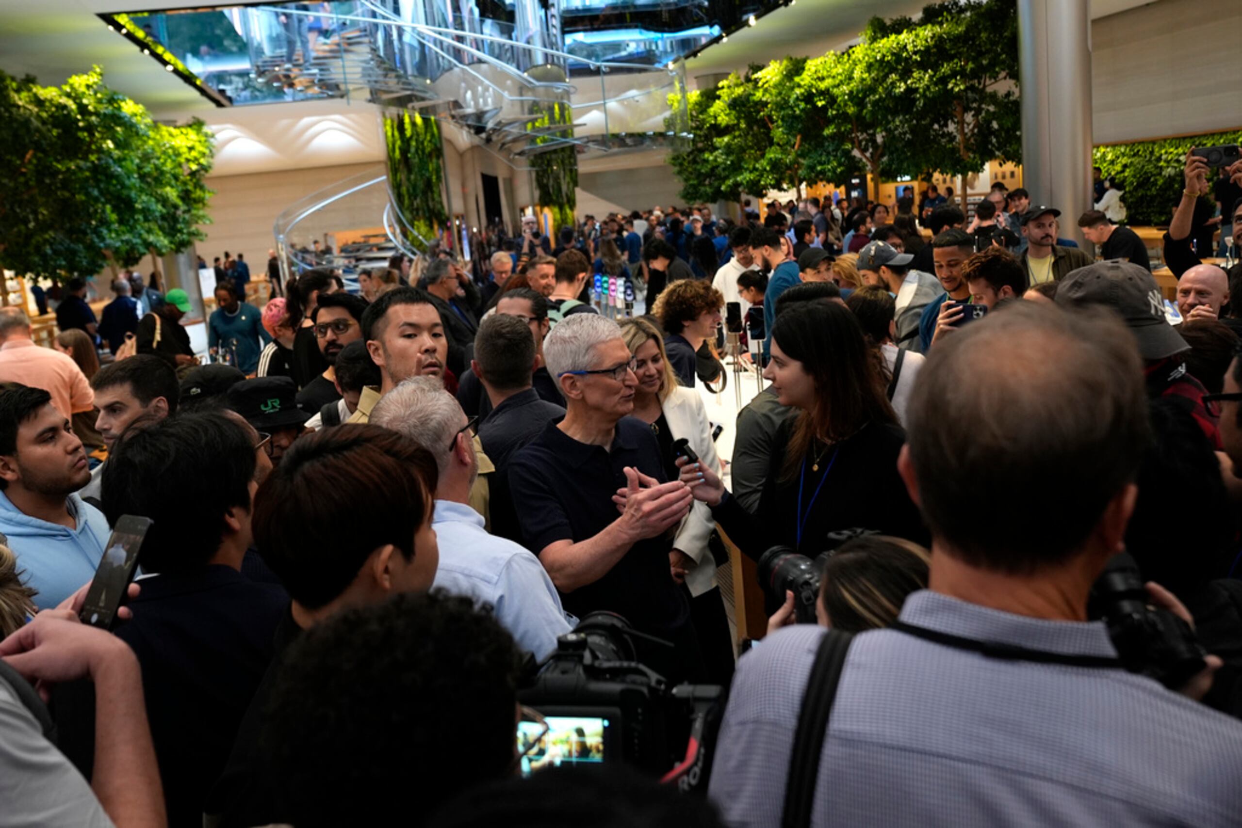 El CEO de Apple, Tim Cook, en el centro, habla con personas en la tienda Apple de la Quinta Avenida durante el lanzamiento del iPhone 16 este viernes en Nueva York.