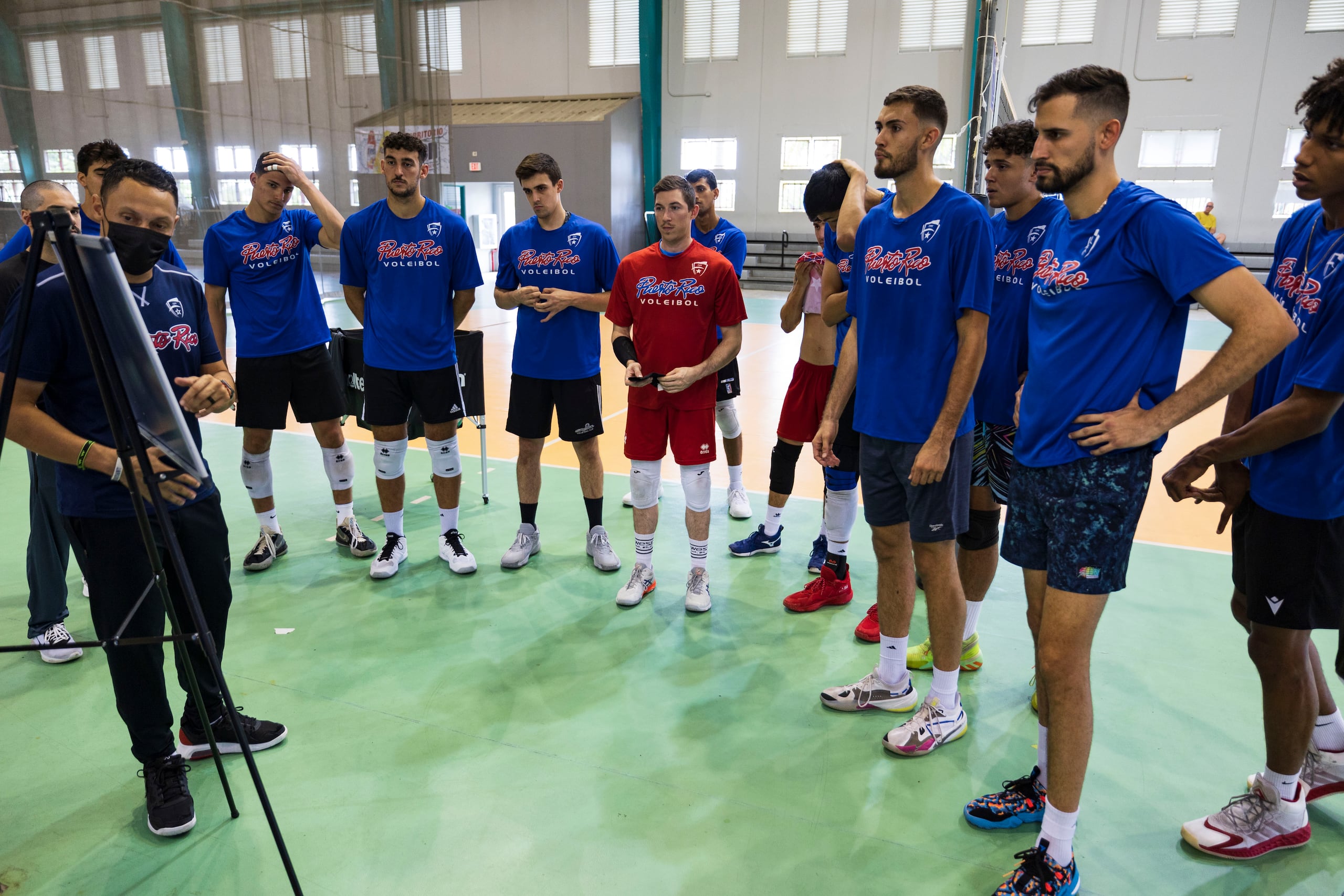 La preselección masculina de voleibol escucha y observa el bosquejo del asistente Jamille Torres en una práctica del Equipo Nacional en 2022.