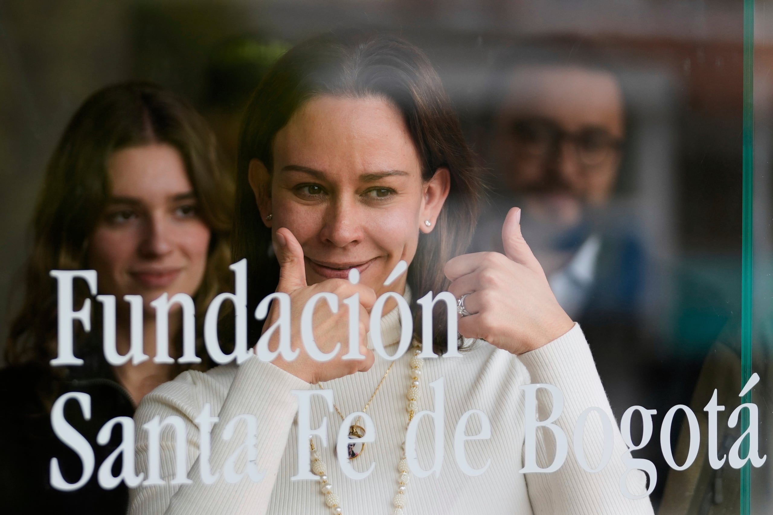 Maria Claudia Tarazona, esposa del precandidato y senador colombiano Miguel Uribe Turbay, interactúa con simpatizantes a través de la ventana en la clínica donde su esposo es asistido luego de haber sido malherido a tiros en un mitin en Bogotá, Colombia.