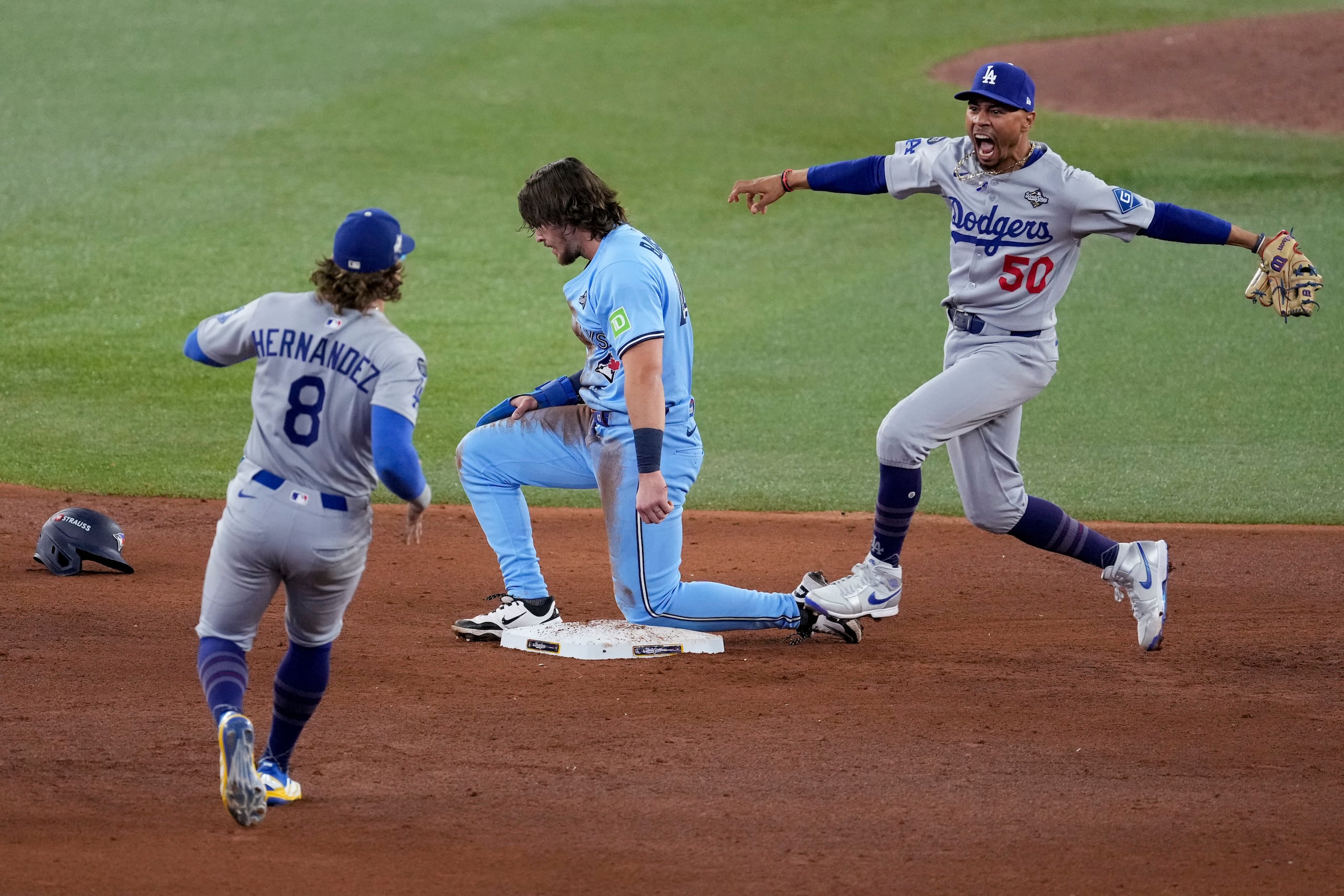 Mookie Betts, de frente, celebra tras completarse una doble matanza originada por el boricua Kike Hernández, quien se acerca a él para celebrar, que dio fin al partido y a una seria amenaza de los Blue Jays en el sexto juego de la Serie Mundial del 2025.