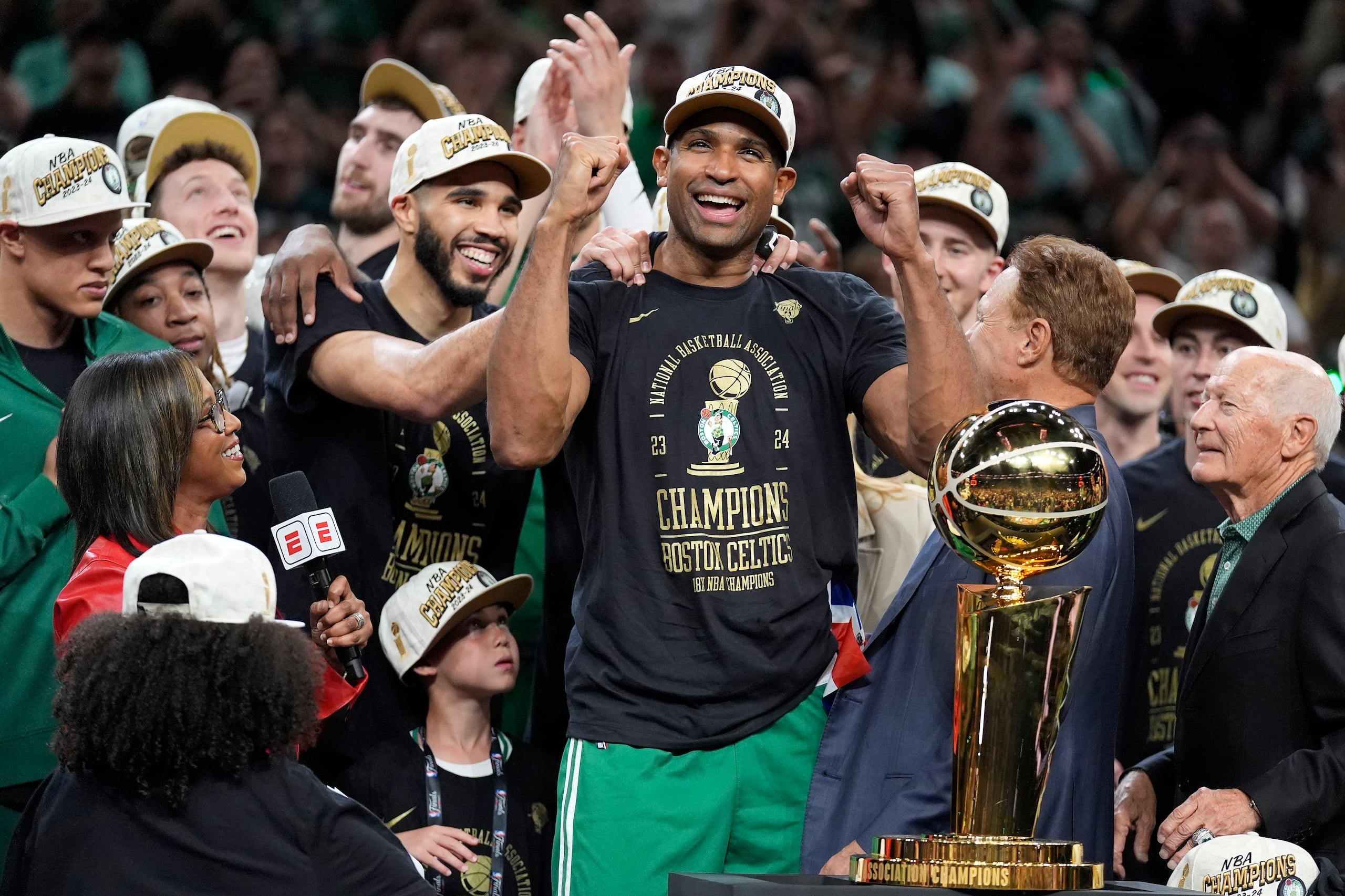 Al Horford, al centro, y Jayson Tatum, con las manos sobre sus hombros, celebran cerca del Larry O'Brien Championship Trophy que reclamaron los Celtics anoche.