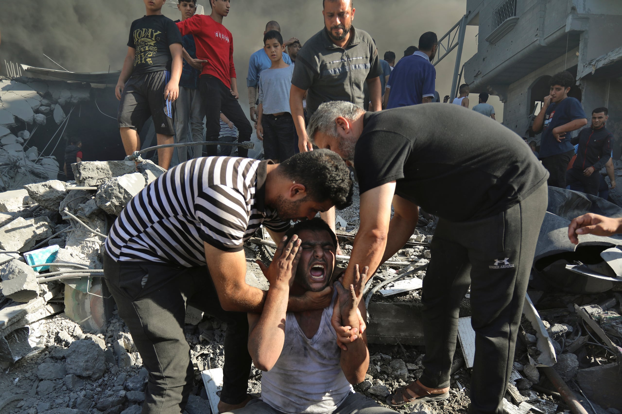 Dos palestinos consuelan a un hombre que llora tras perder familiares bajo los escombros, de una casa destruida tras un ataque aéreo israelí en Ciudad de Gaza, el sábado 4 de noviembre de 2023. (AP Foto/Abed Khaled)