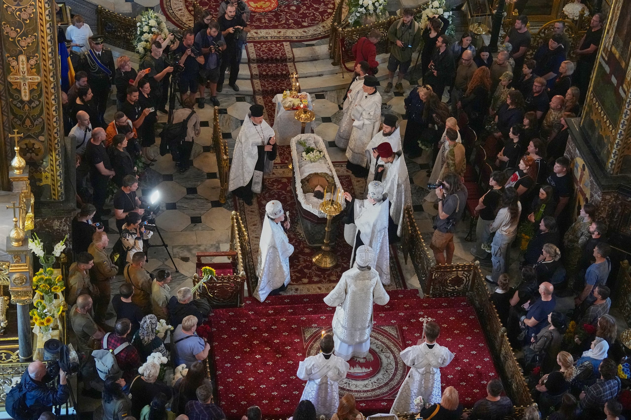Sacerdotes ofician la ceremonia de despedida de Oleksiy Yukov, quien murió cuando exhumaba los cadáveres de soldados caídos en el frente de la región de Donetsk, en la catedral de San Vladimiro de Kiev, Ucrania, el sábado, 8 de agosto. (Foto AP/Efrem Lukatsky)