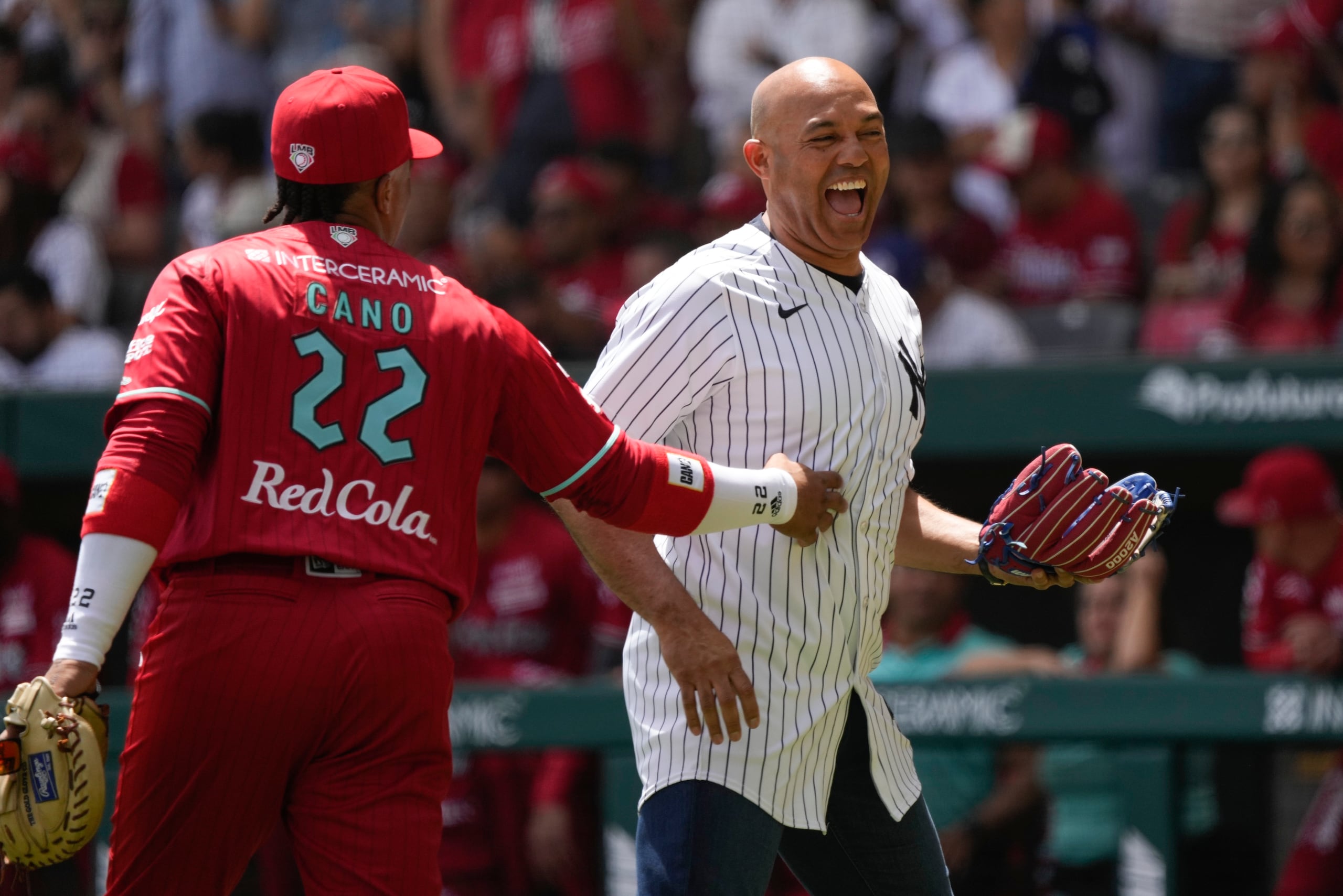 Robinson Canó, segunda base de los Diablos Rojos, cruza palabras y saludos con su excompañero en los Yankees, Mariano Rivera, quien hizo el lanzamiento de honor en el partido.