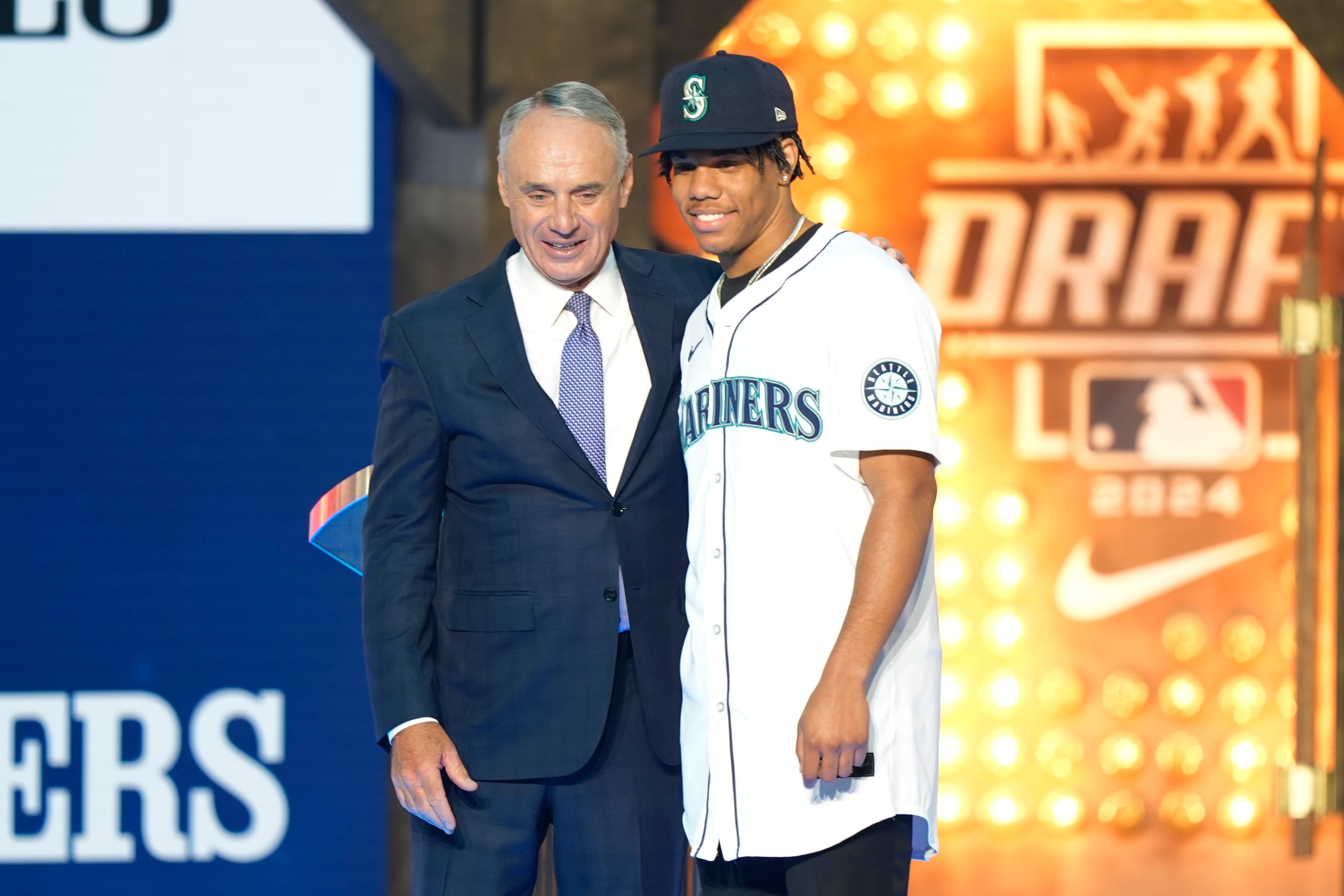 El comisionado del Béisbol de Grandes Ligas, Rob Manfred, izquierda, y Jurrangelo Cijntje, posan después de que Cijntje fuera seleccionado en el puesto 15 por los Marineros de Seattle en la primera ronda del draft de béisbol de la MLB en Fort Worth, Texas, el domingo 14 de julio de 2024.