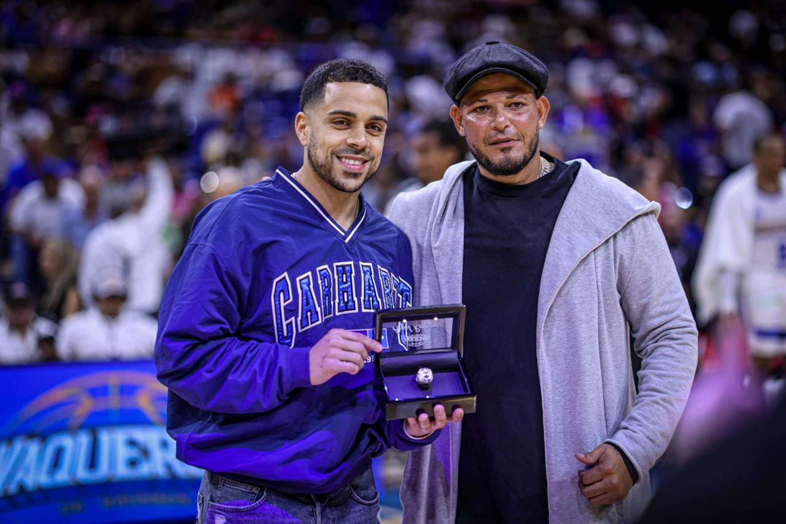 Ángel Rodríguez posa junto al apoderado de los Vaqueros, Yadier Molina, y el anillo de campeón de 2022.