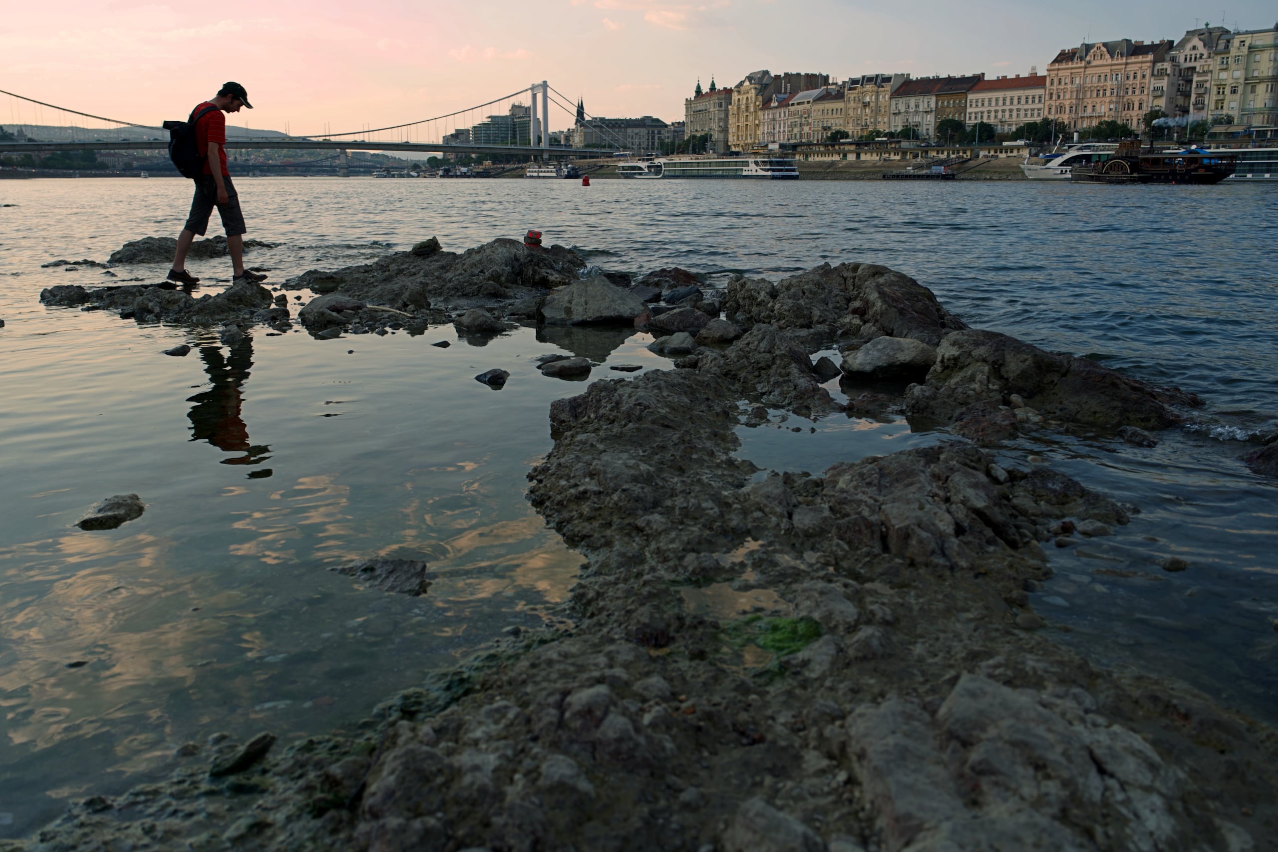 Un hombre camina sobre rocas que emergen del Danubio en el centro de Budapest, Hungría, ya que el río, que atraviesa 10 países europeos, ha descendido a niveles de agua históricamente bajos. (AP Foto/Bela Szandelszky)