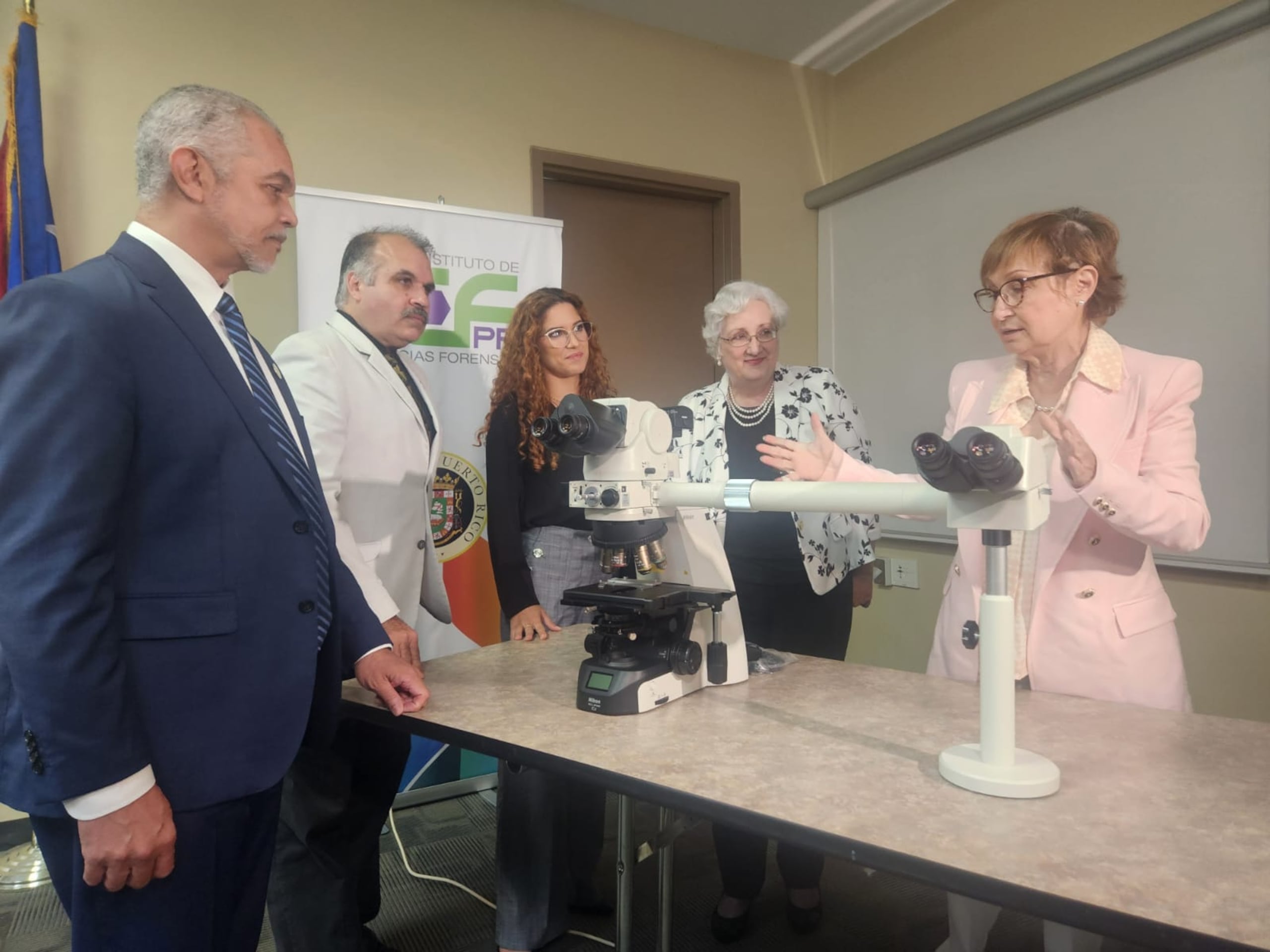 La directora de Instituto de Ciencias Forenses, María Conte Miller, presenta el microscopio que se adquirió para poder enseñar a la nueva residente, Paola Luna García (en el centro).
