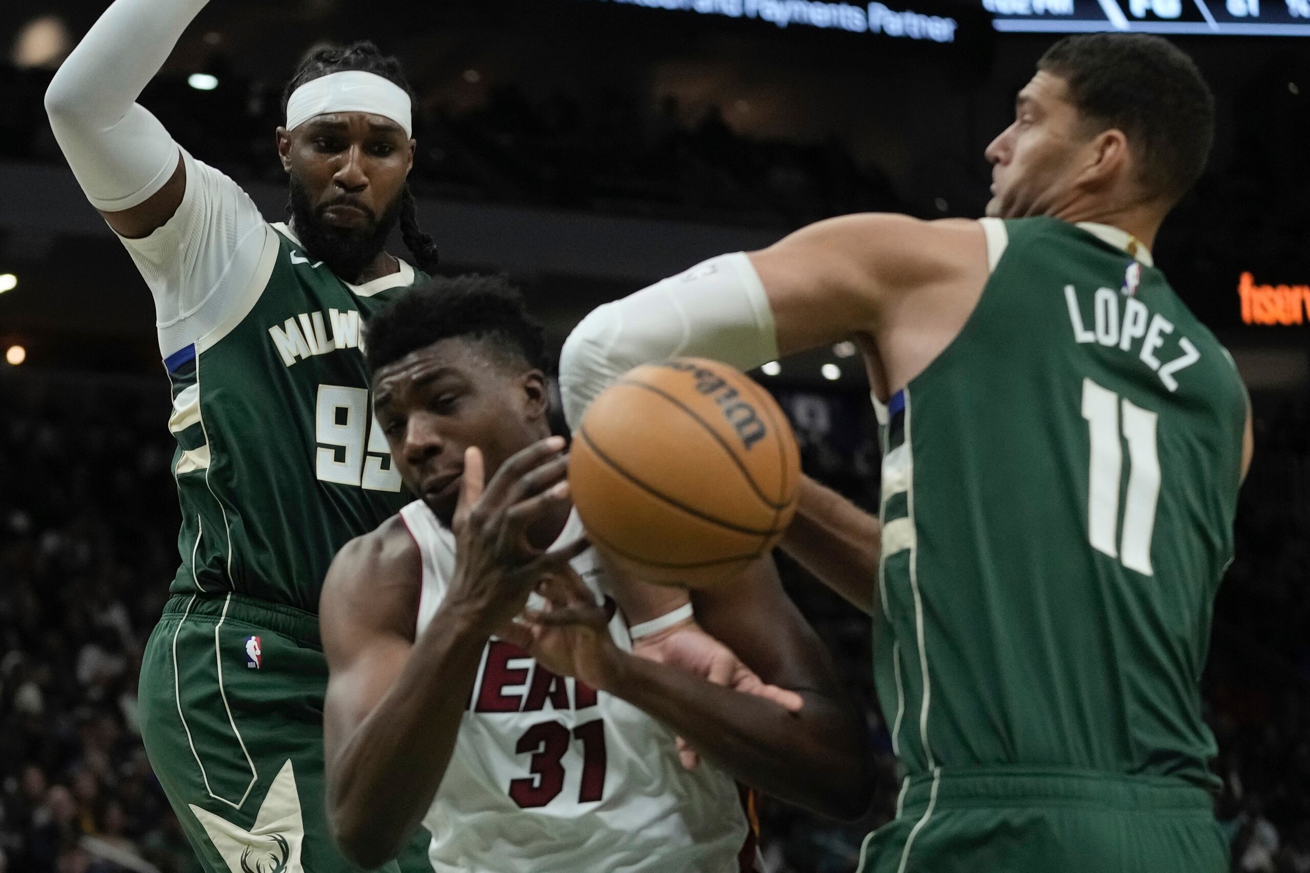 Thomas Bryant, del Heat de Miami, pierde la pelota entre sus rivales de los Bucks de Milwaukee Jae Crowder y Brook Lopez durante la primera mitad del juego de la NBA que enfrentó a ambos equipos el 30 de octubre de 2023, en Milwaukee. (AP Foto/Morry Gash)