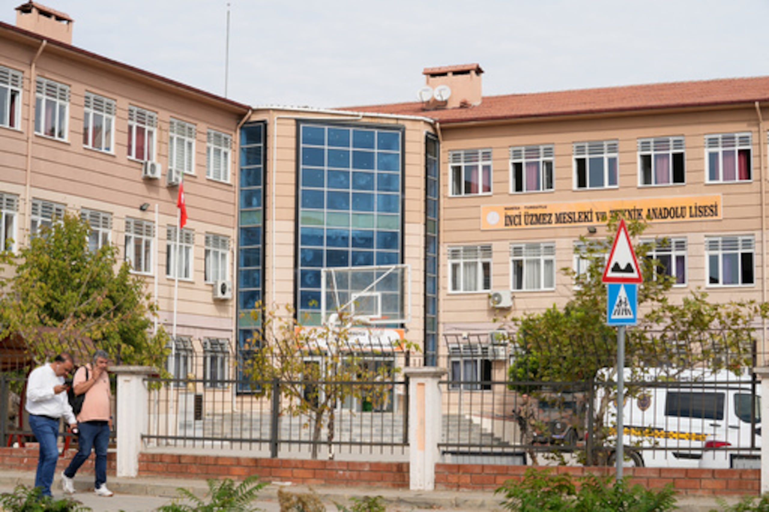 Varias personas pasan junto a un instituto de formación profesional y técnica en el distrito de Turgutlu, en la provincia de Manisa, al oeste de Turquía, el martes 22 de septiembre de 2026, después de que un hombre armado abriera fuego cerca del centro. (IHA vía AP)