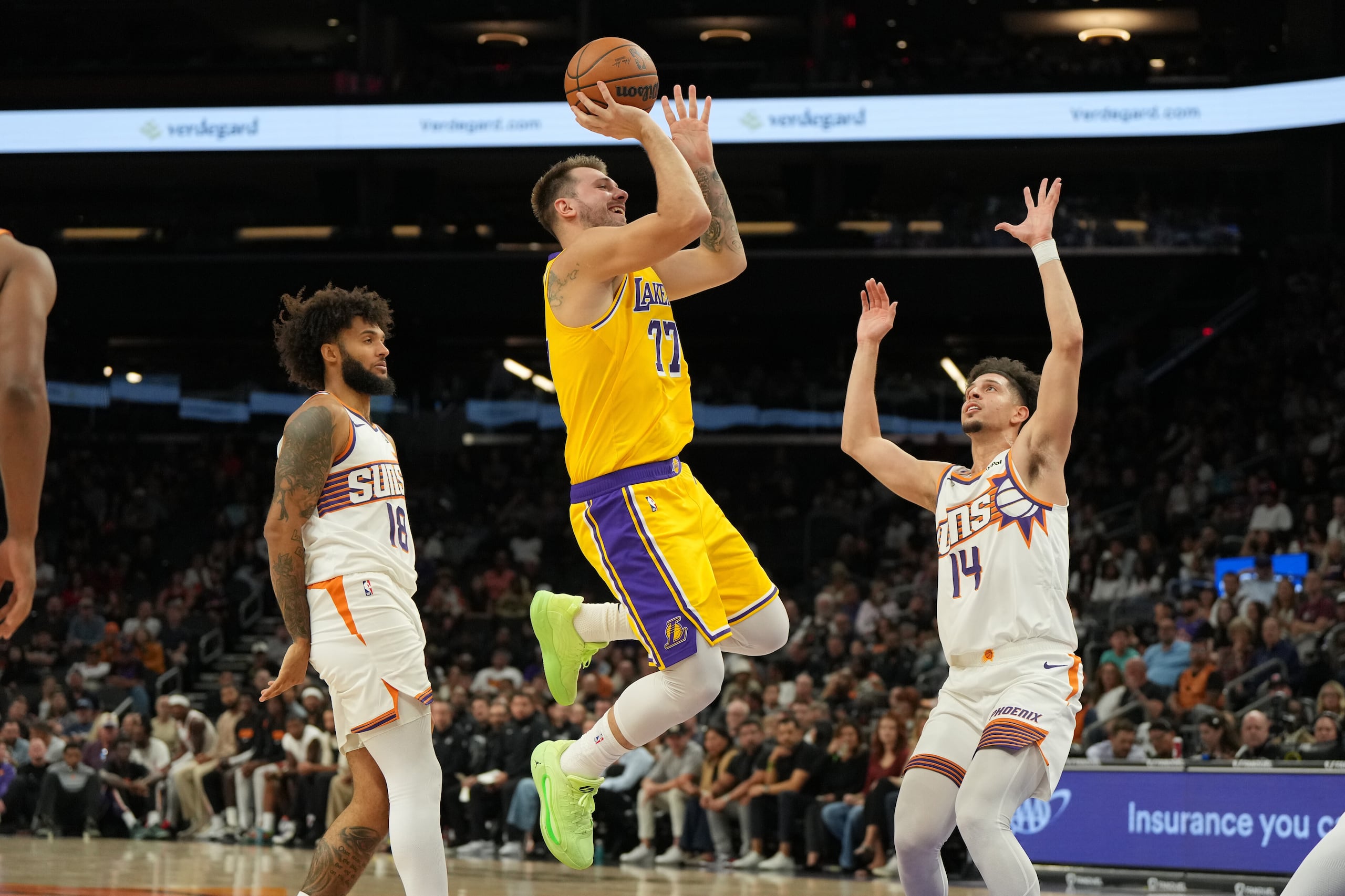 El alero de los Lakers de Los Ángeles Luka Dončić lanza el balón sobre Isaiah Livers y Joby Brea de los Suns de Phoenix en el encuentro de pretemporada del martes 14 de octubre del 2025. (AP Foto/Rick Scuteri)