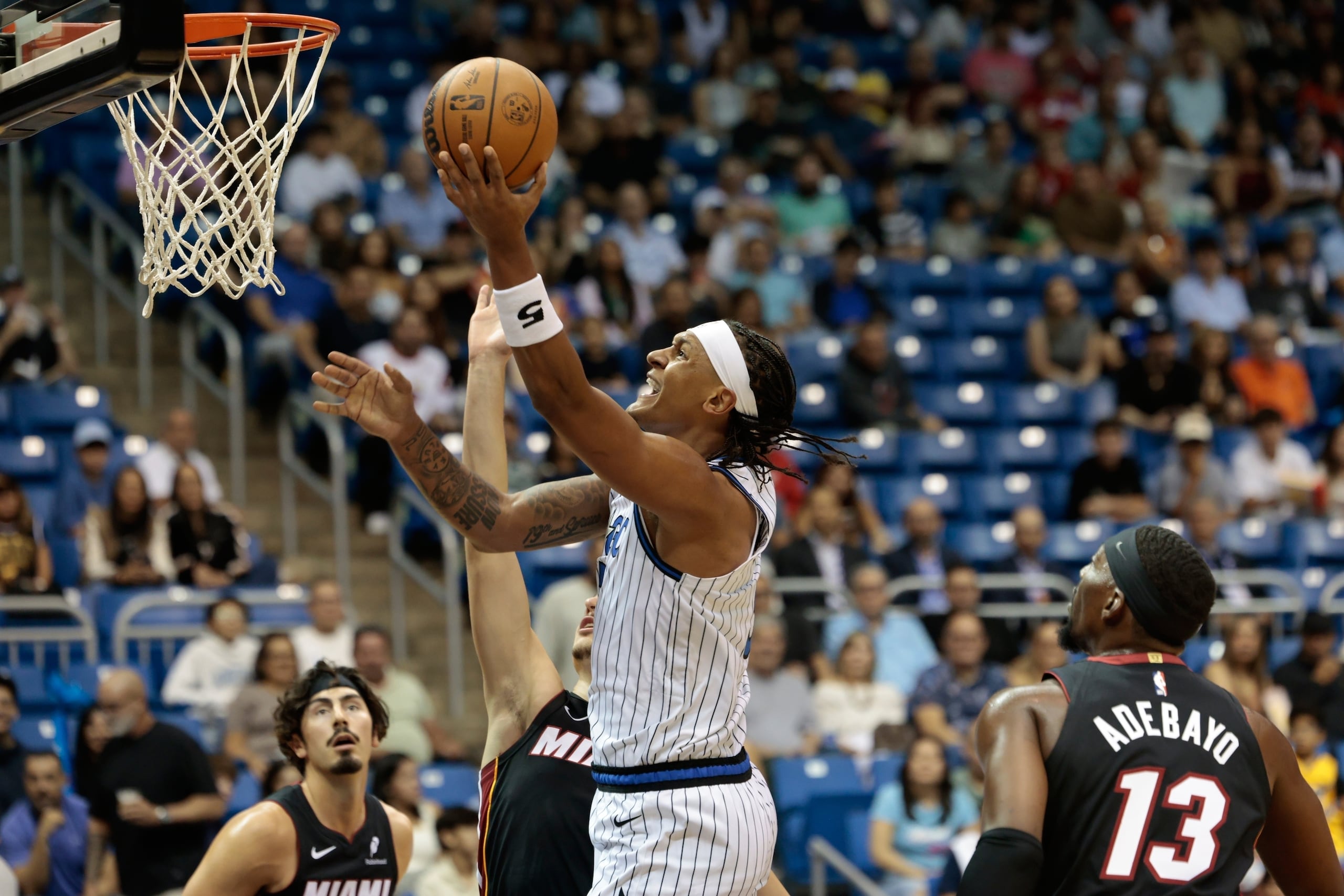 Paolo Banchero, al centro, alero del Magic de Orlando, ataca el aro frente al Heat de Miami durante la primera mitad del juego de pretemporada de baloncesto de la NBA, el sábado 4 de octubre de 2025, en San Juan, Puerto Rico. (AP Foto/Alejandro Granadillo)