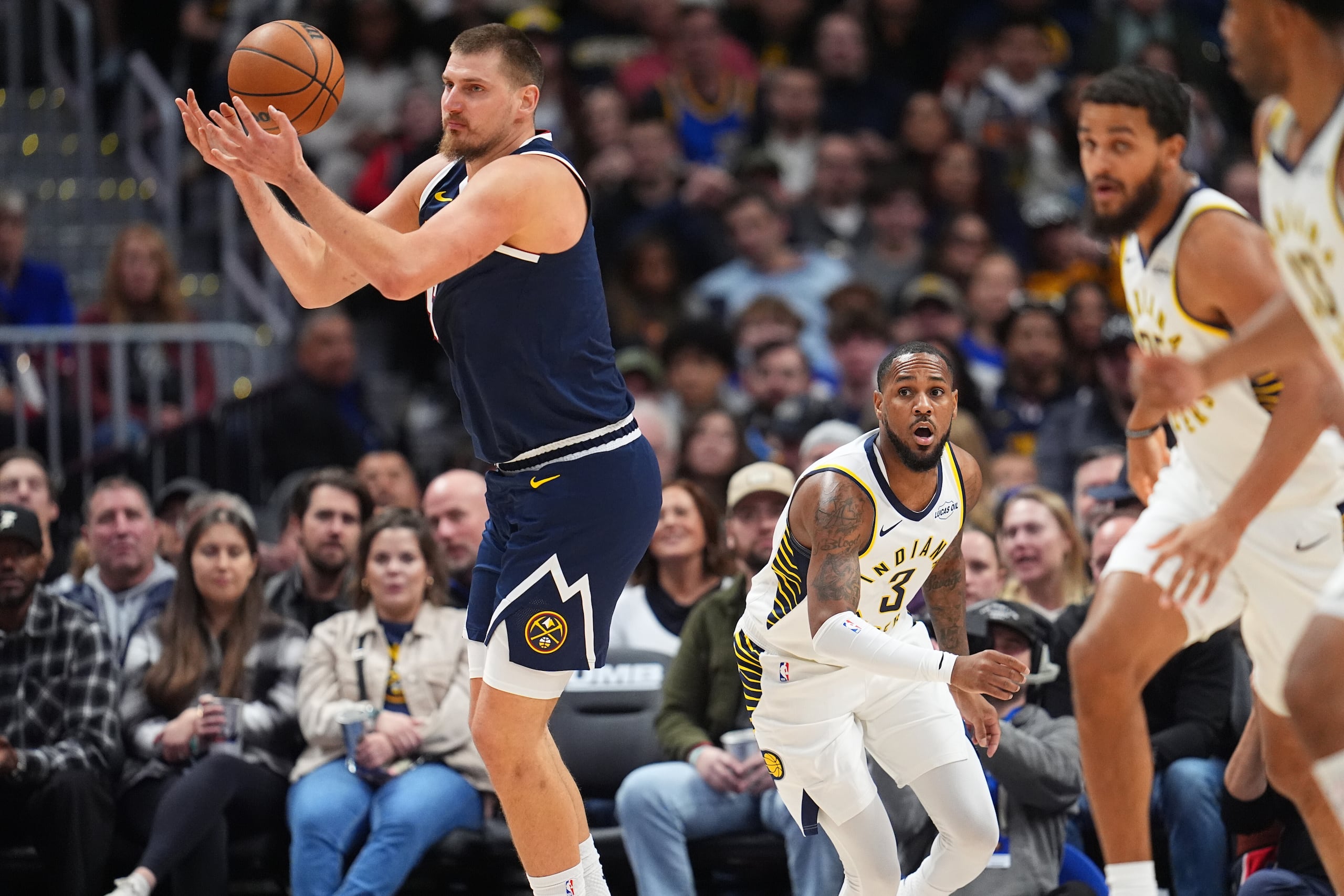 El serbio Nikola Jokic, de los Nuggets de Denver, atrapa un balón perdido frente a Monte Morris, de los Pacers de Indiana, el sábado 8 de noviembre de 2025, en la NBA (AP foto/David Zalubowski)