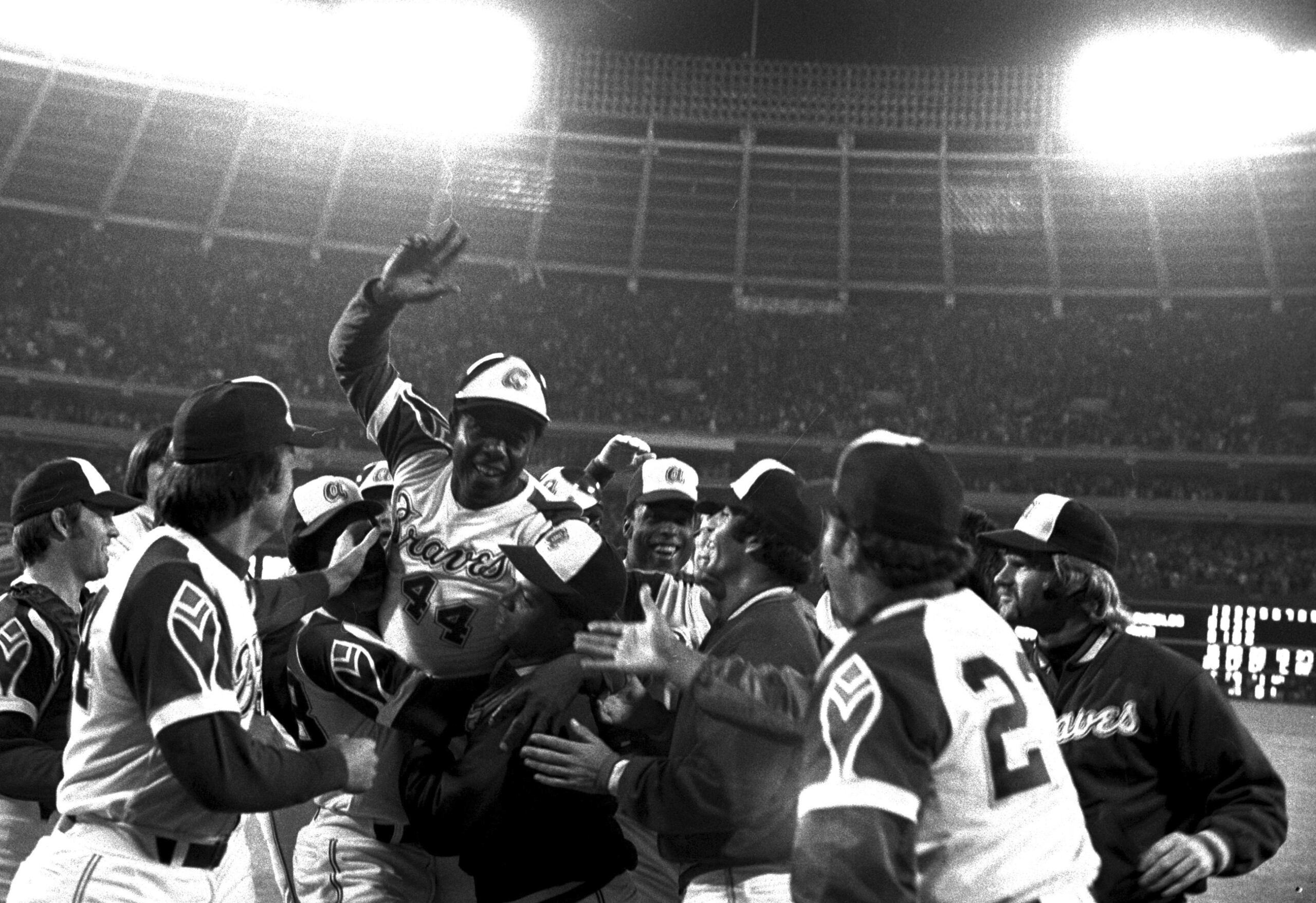 Los compañeros de Hank Aaron lo levantan en brazos luego de fijar el récord de jonrones en las Mayores. Existía mucho temor de que alguien pudiera querer matar a Aaron por ser un hombre de la raza negra quien quebraba el récord de Babe Ruth.