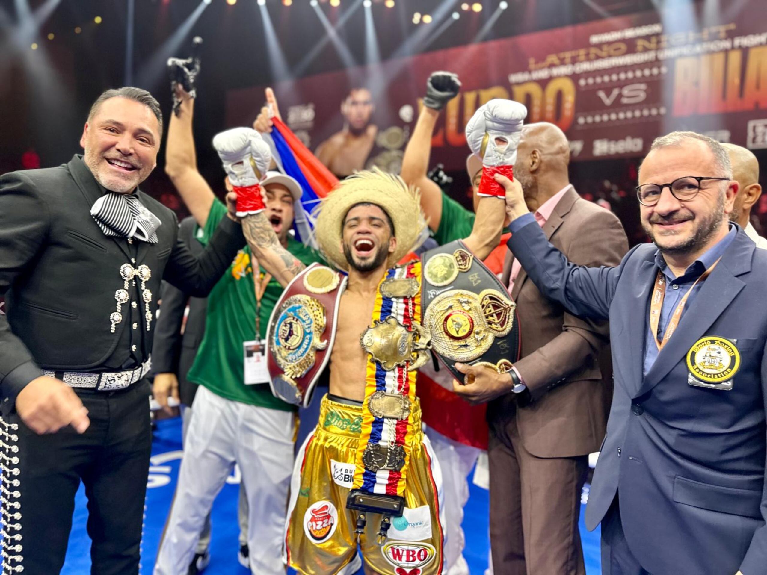 Oscar Collazo, levanta los brazos en señal de triunfo, ahora con ambas correas de campeón en sus brazos.