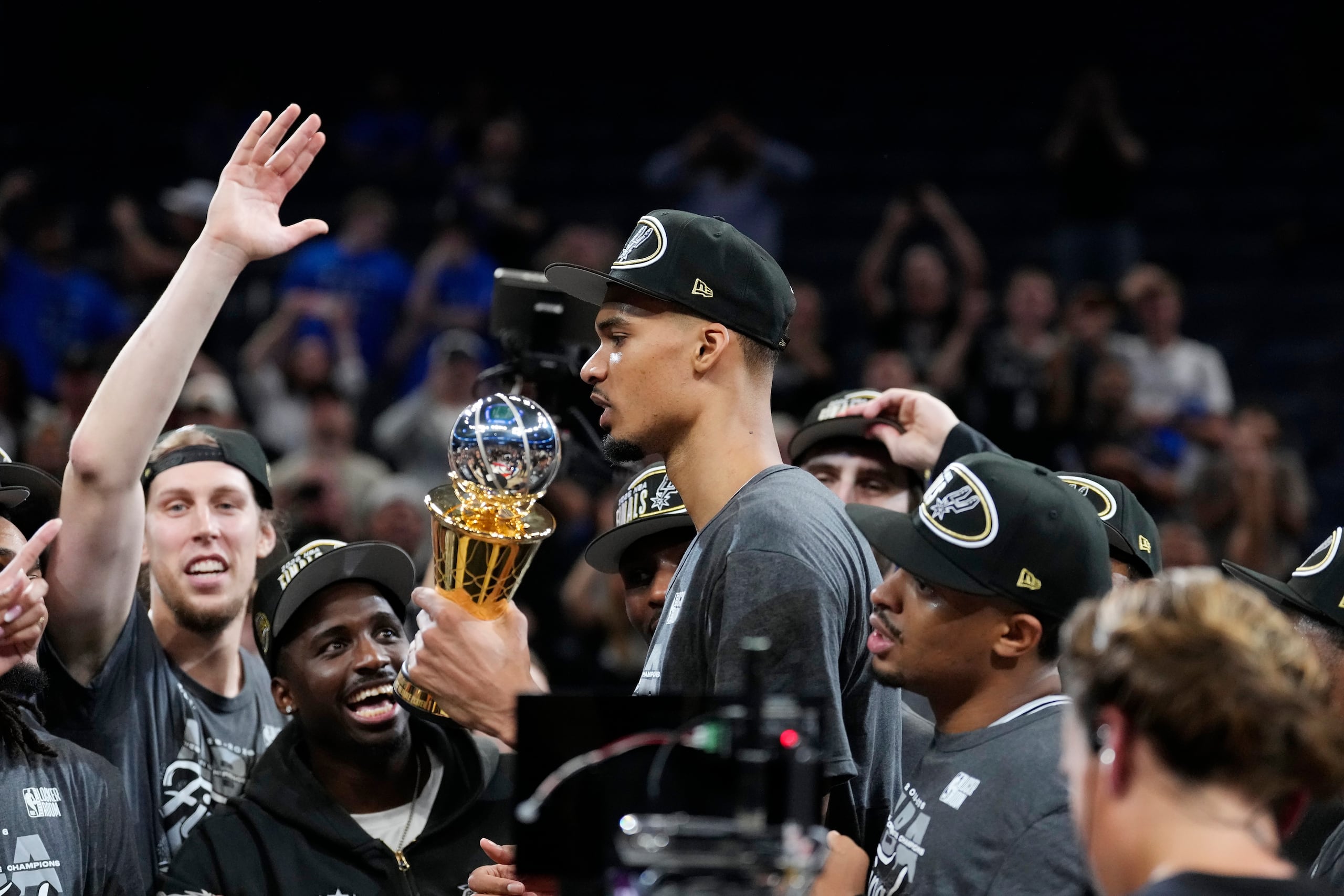 El alero de los Spurs de San Antonio, Victor Wembanyama, sostiene el trofeo de MVP mientras celebra con sus compañeros de equipo.