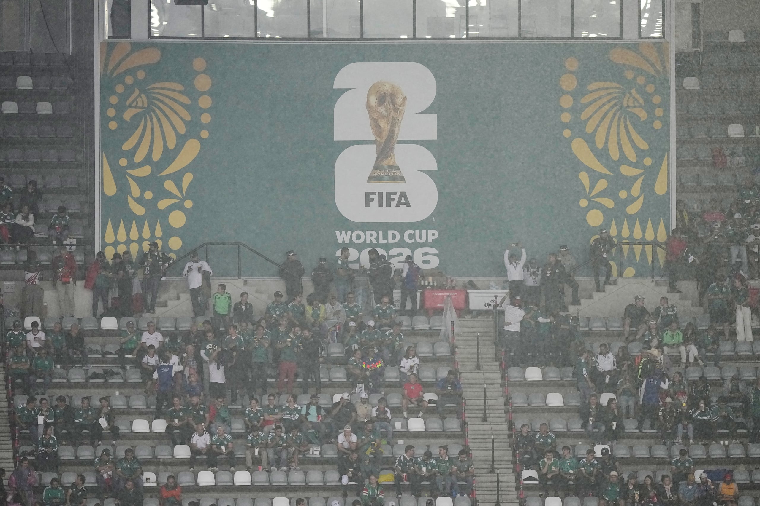 Los aficionados esperan a que pase la lluvia mientras el partido entre México e Inglaterra, correspondiente a los octavos de final del Mundial de Fútbol, se retrasa debido al mal tiempo en la Ciudad de México, el domingo 5 de julio de 2026. (Foto AP/Fernando Llano)