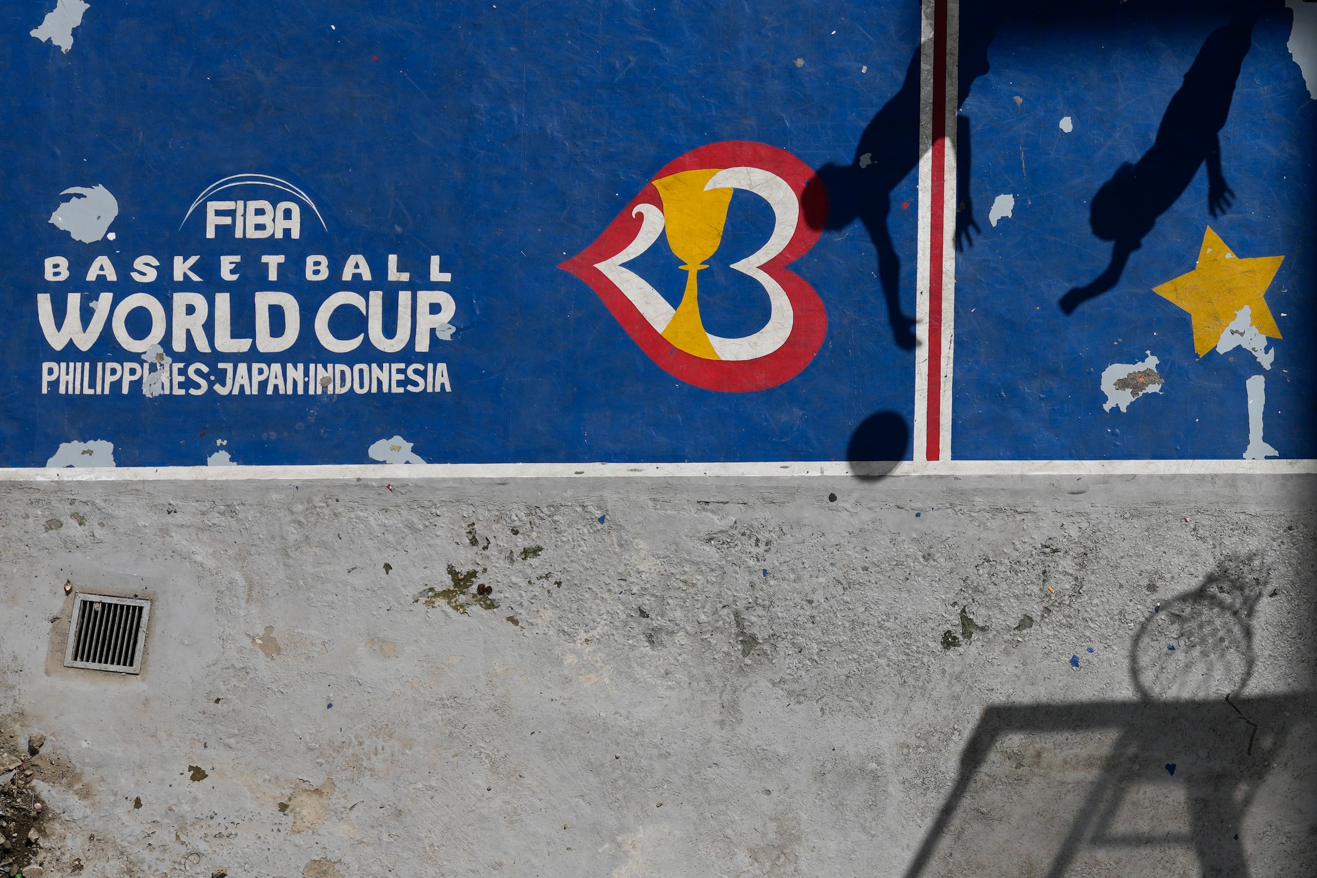 Las sombras de dos jugadores se reflejan en una cancha pintada con los colores de la Copa del Mundo de la FIBA.