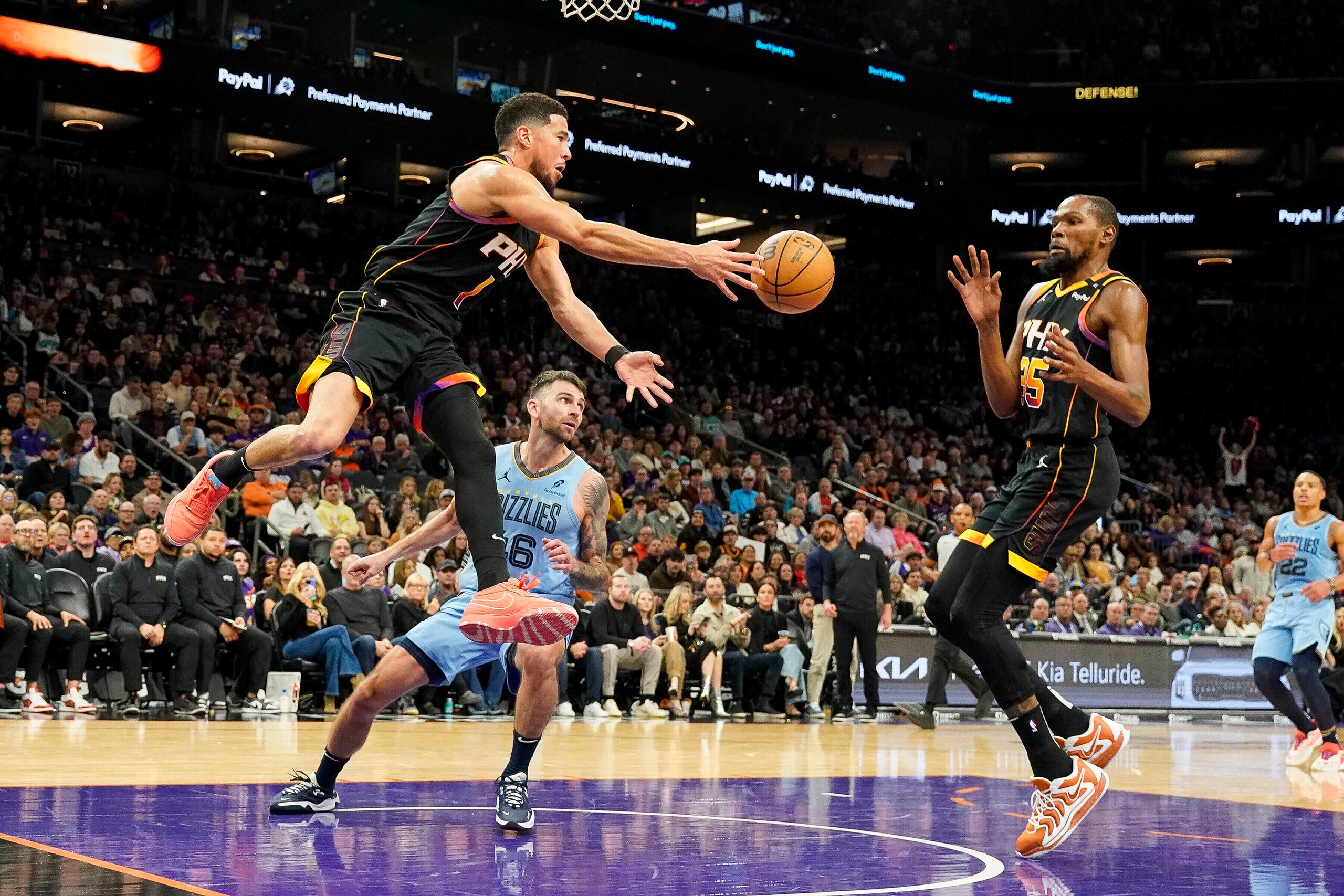 Devin Booker, a la izquierda, pasa el balón a Kevin Durant, a la derecha, ambos de los Suns de Phoenix.