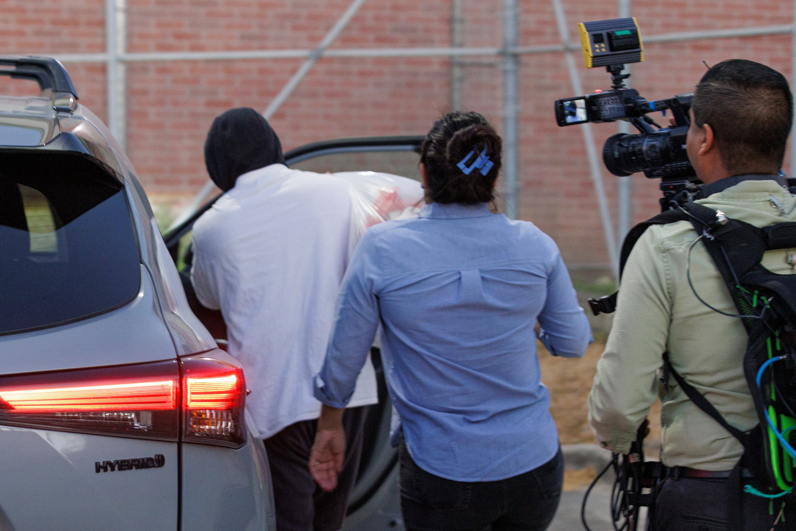 El agente de inmigración Christian Castro sube a un coche rodeado de periodistas momentos después de salir del Centro de Detención Carrizalez-Rucker del condado Cameron en Brownsville, Texas, el jueves 27 de agosto de 2026. (Foto AP/Michael Gonzalez)
